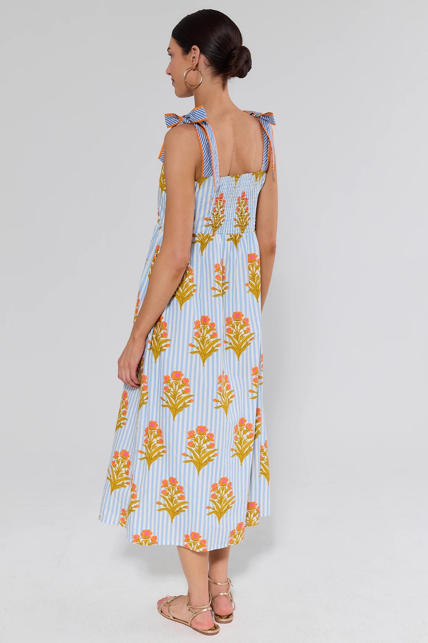 Woman standing wearing a floral dress with a grey background