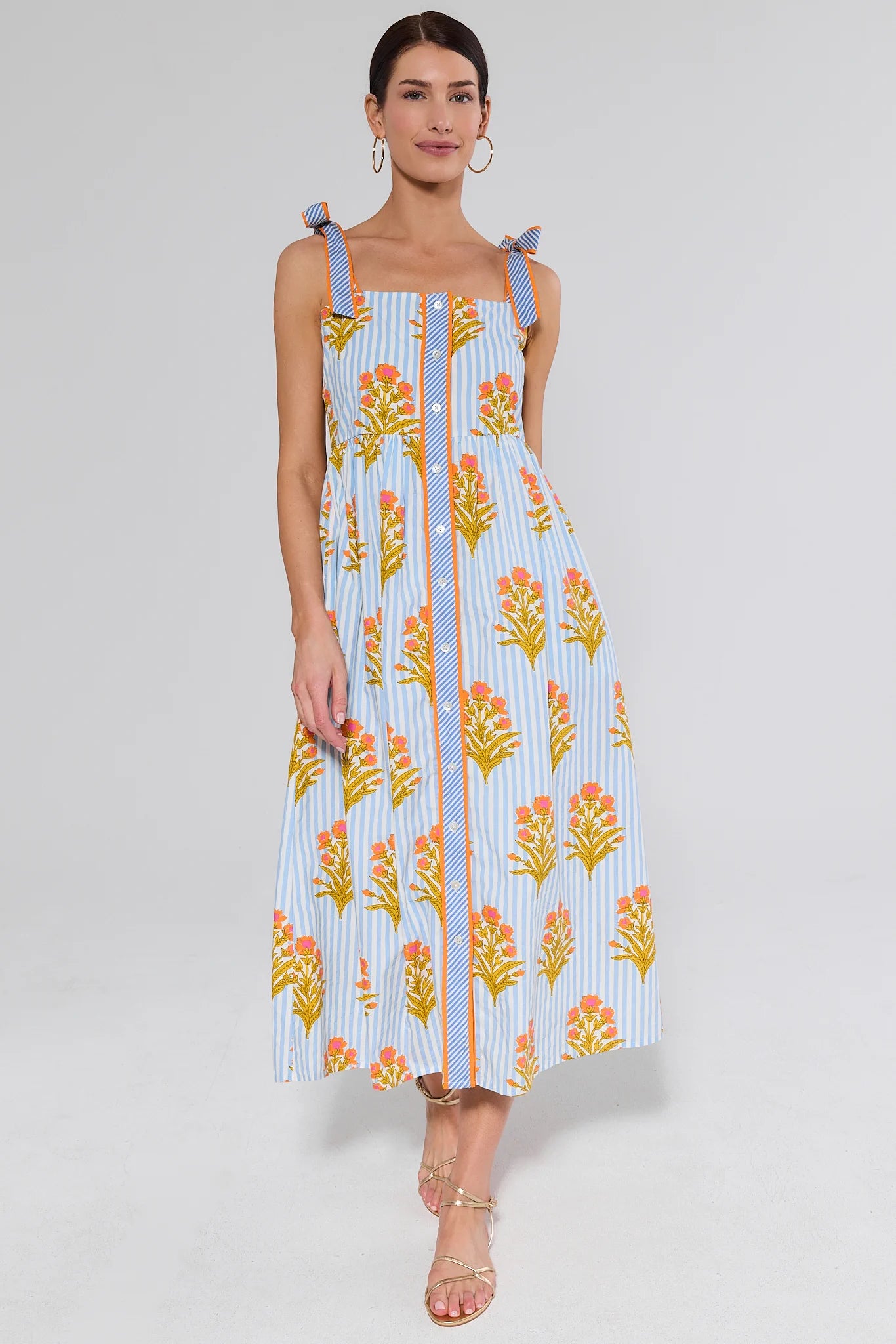 Woman wearing a floral dress and gold sandals with a background