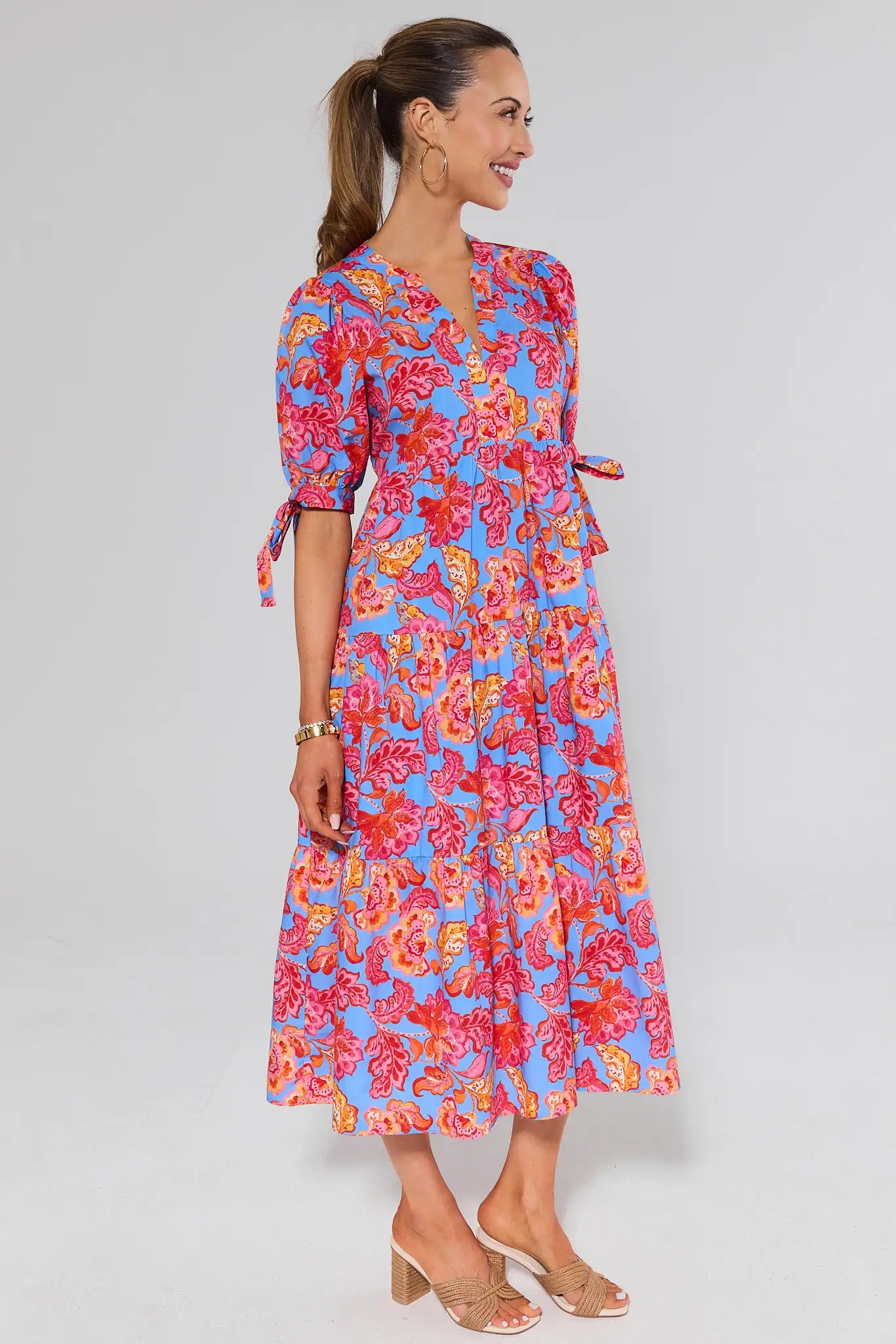 side shot Woman wearing a colorful floral dress on a gray background