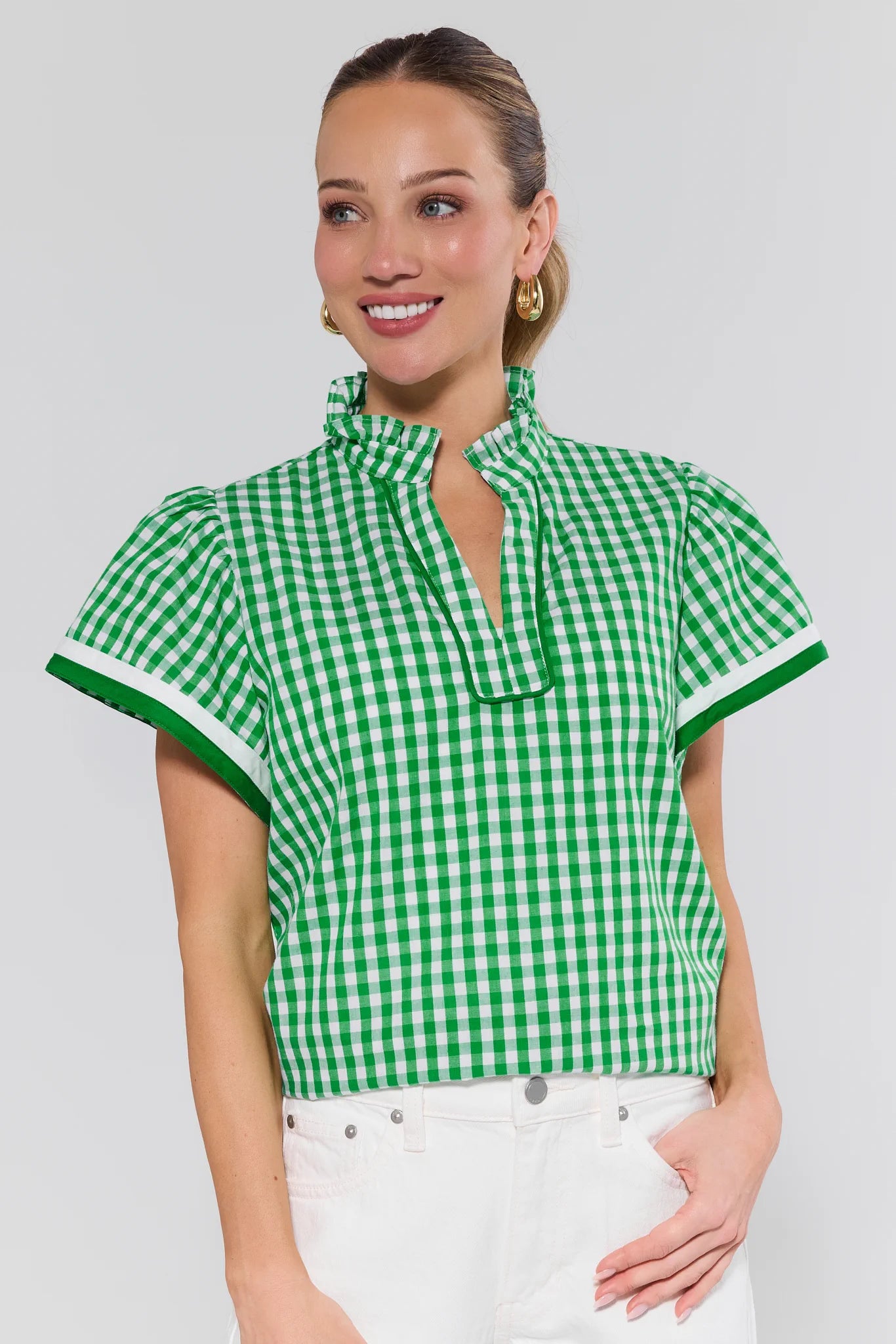 Woman wearing a green and white checkered blouse against a plain background