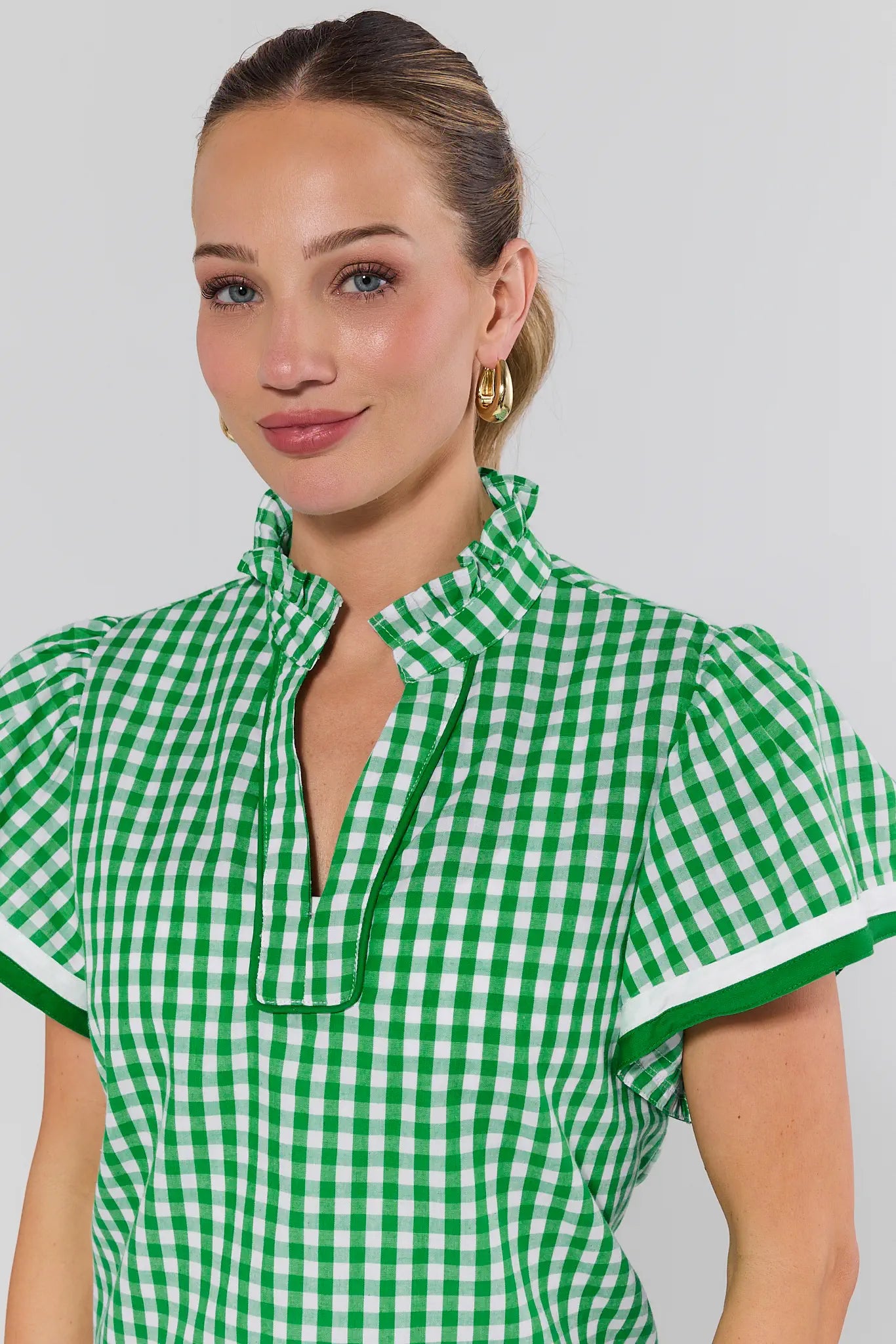 Woman wearing a green and white checkered dress against a plain background