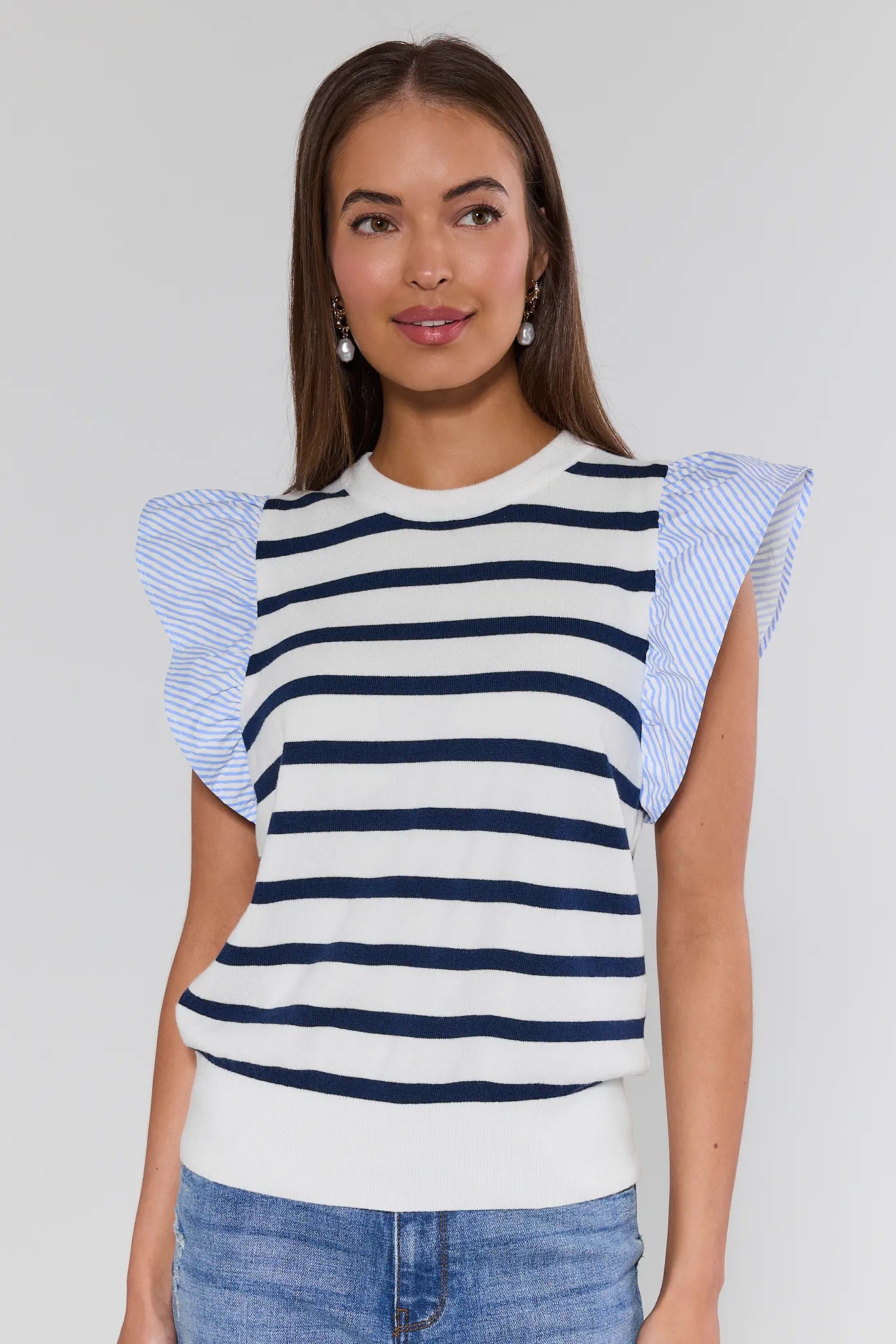 Woman wearing a striped top with ruffled sleeves against a plain background