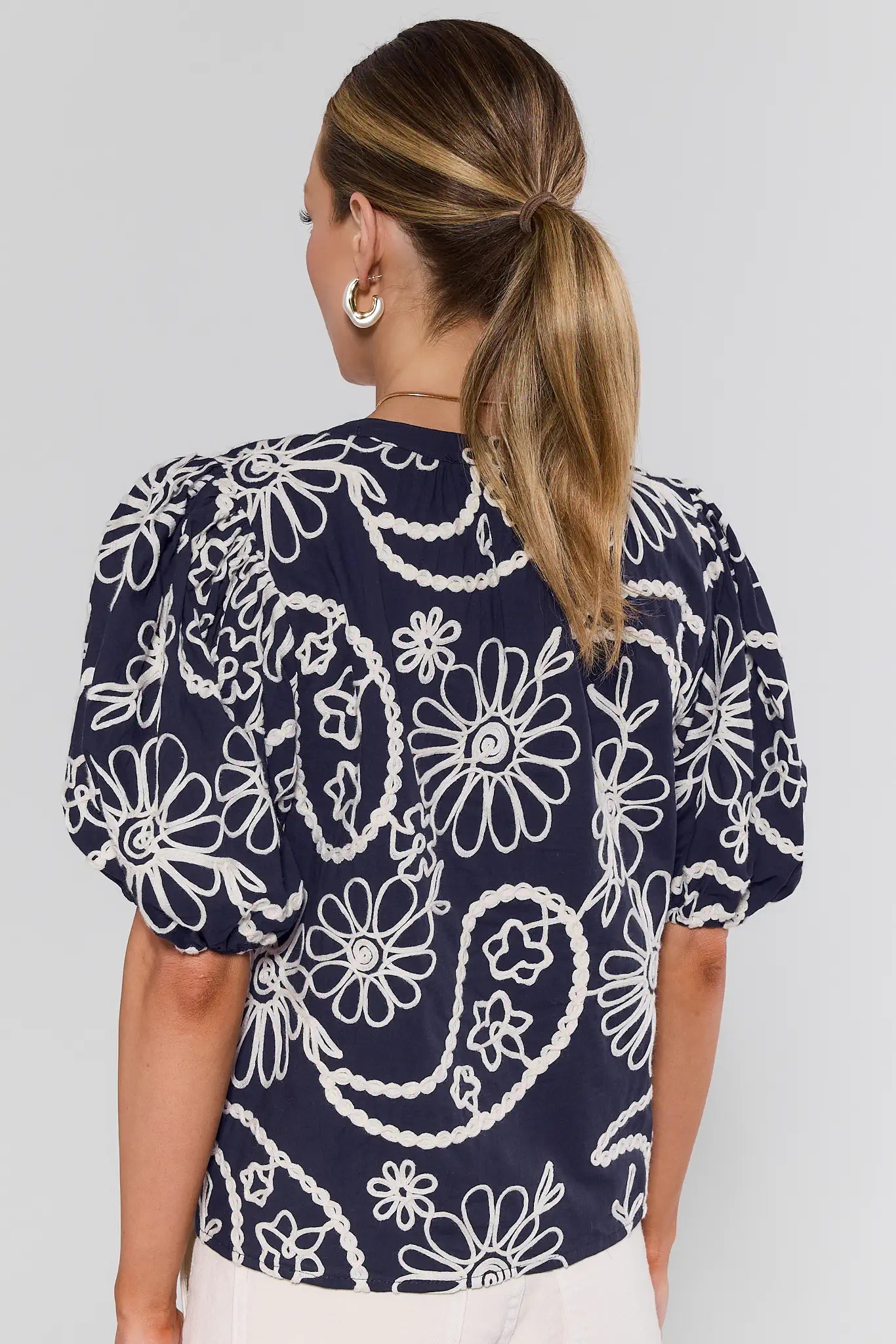 Navy blue top with white floral and paisley pattern worn by a person on a light gray background