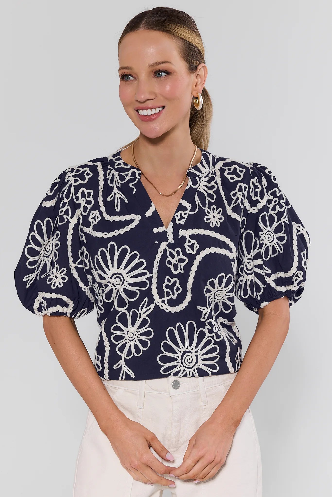 Woman wearing a navy blue blouse with white floral pattern on a plain background