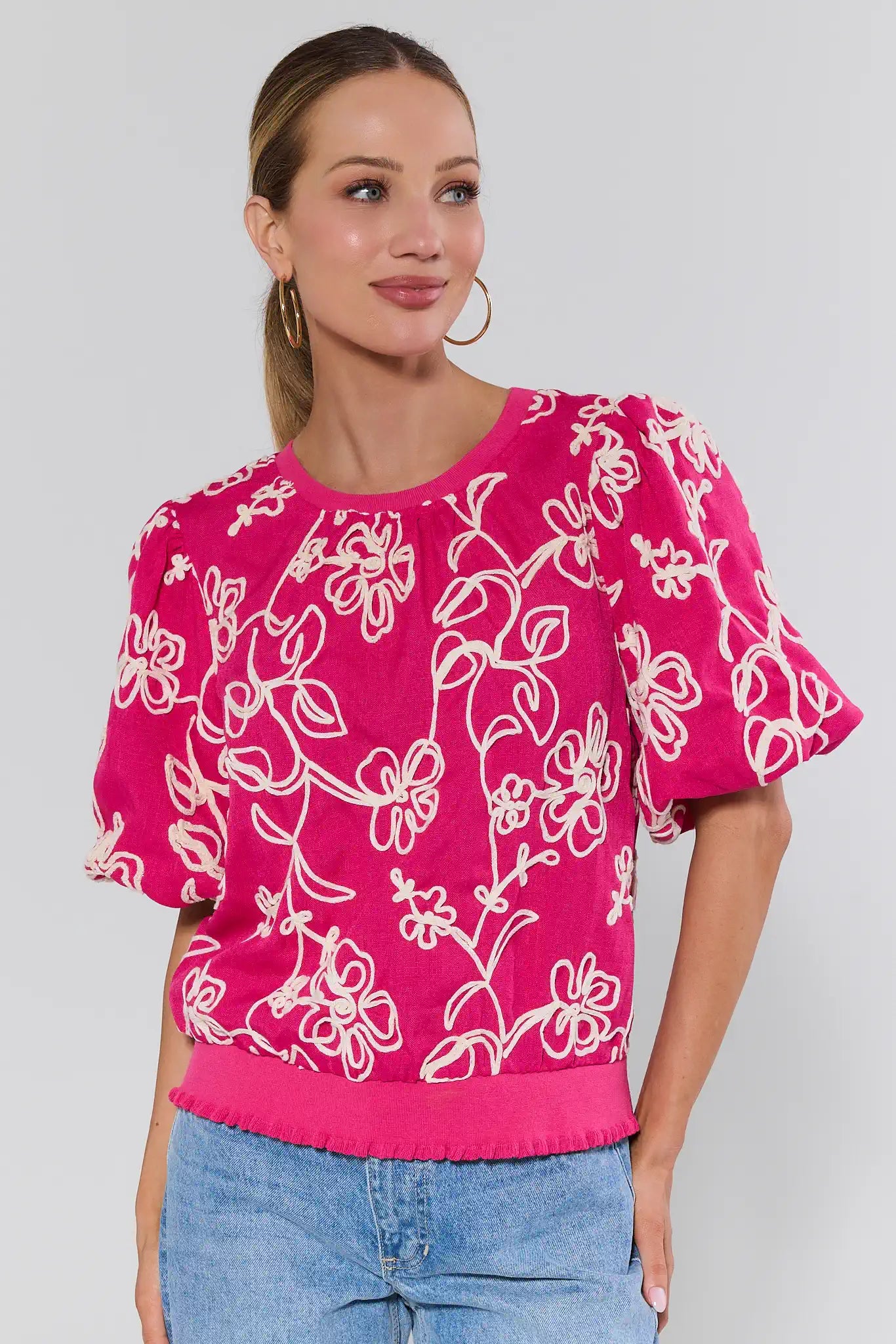 Woman wearing a pink floral blouse with a plain background