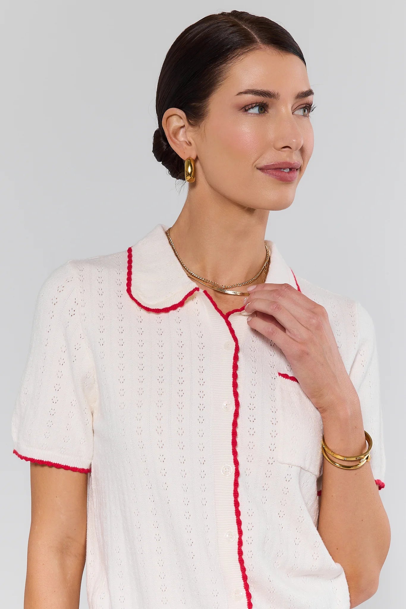 Woman wearing a top with red trim against a plain background