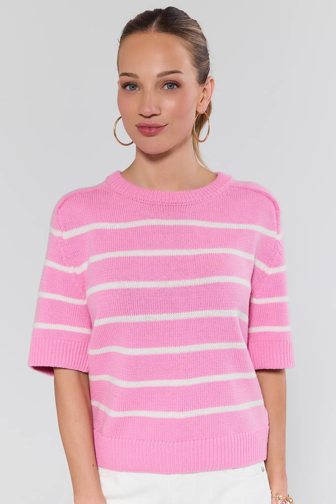 Woman wearing a pink and white striped sweater on a plain background