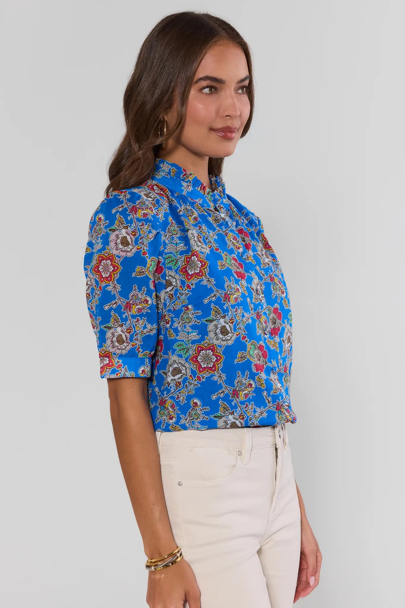 Woman wearing a blue floral blouse against a plain background side