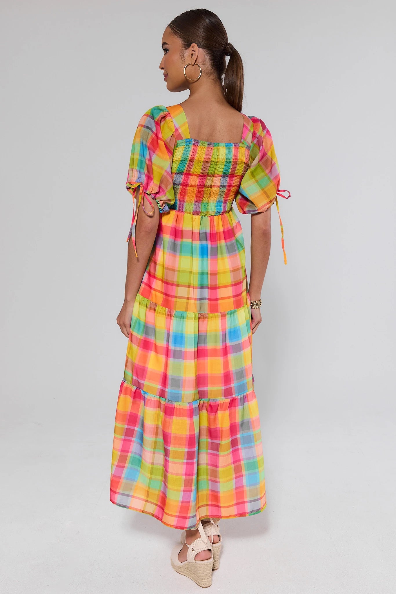 Woman standing wearing a colorful plaid dress on a white background