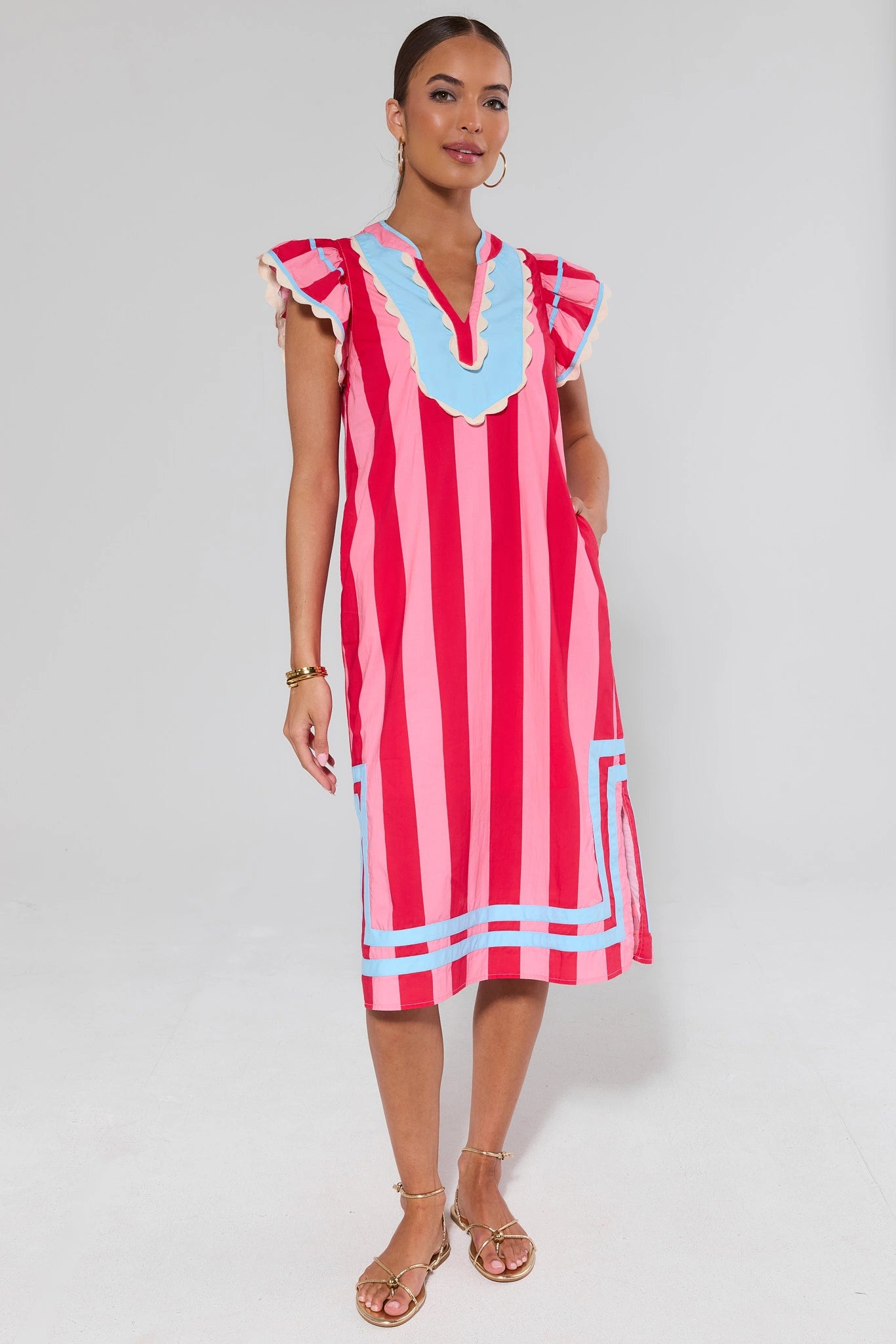 Woman wearing a red and white striped dress with blue accents on a white background
