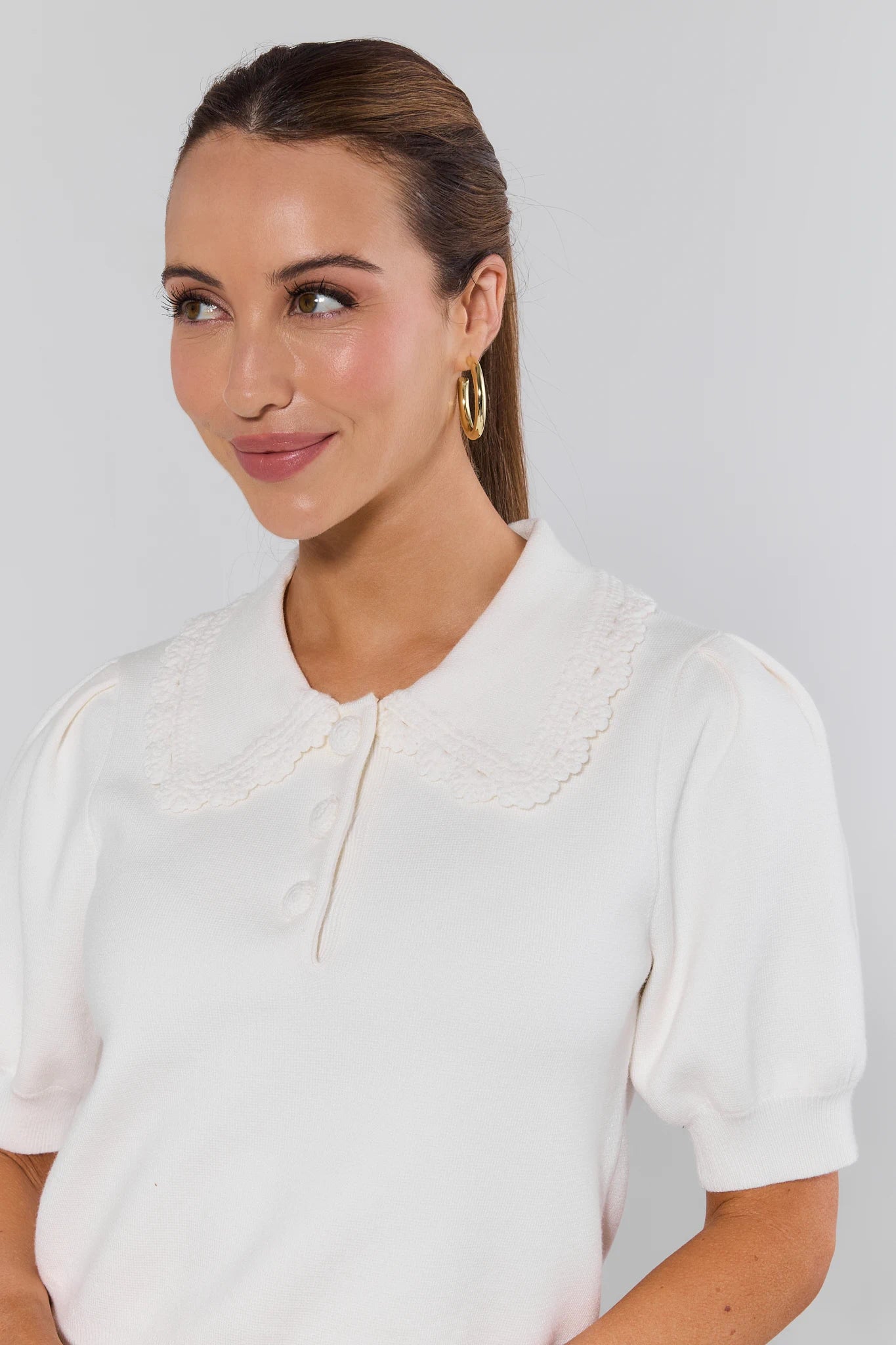 Woman wearing a white blouse against a plain background