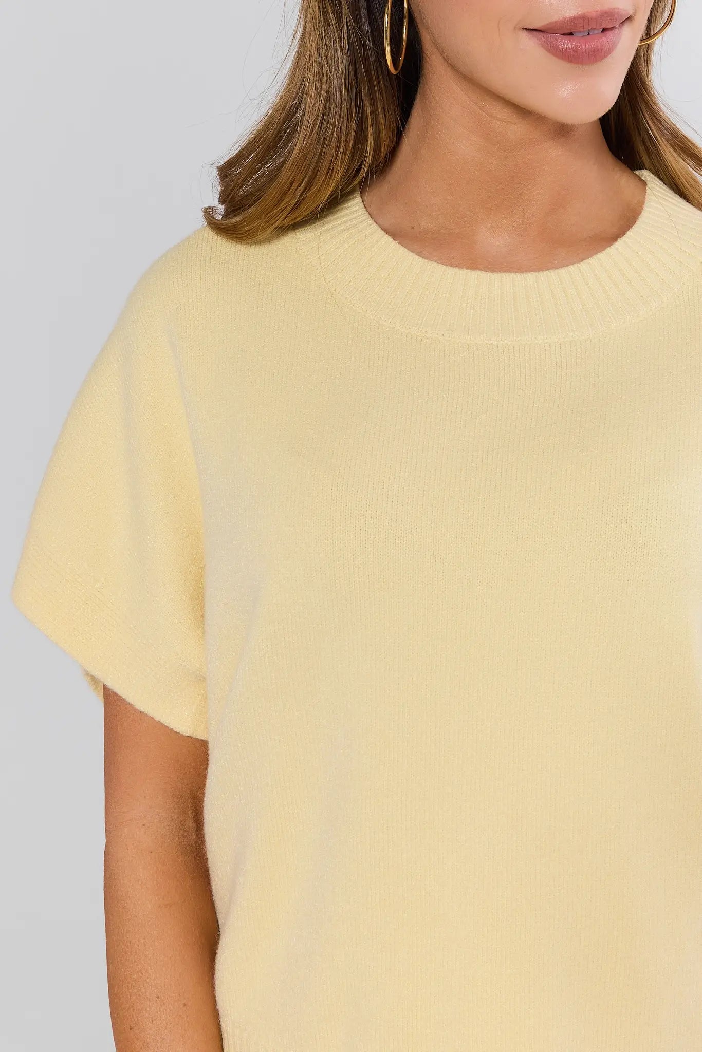 Yellow sweater worn by a person on a plain background