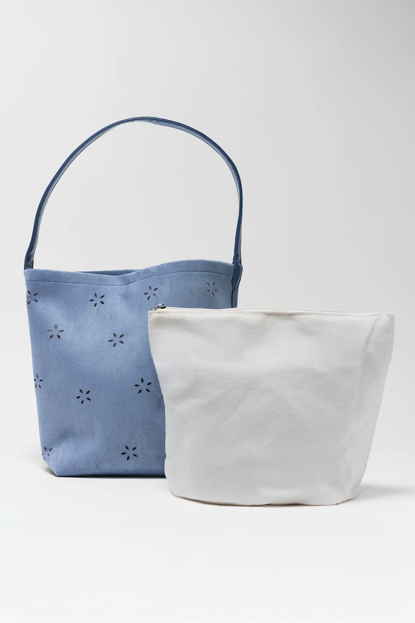 Two fabric bags, one blue with floral patterns and one white, on a light gray background.