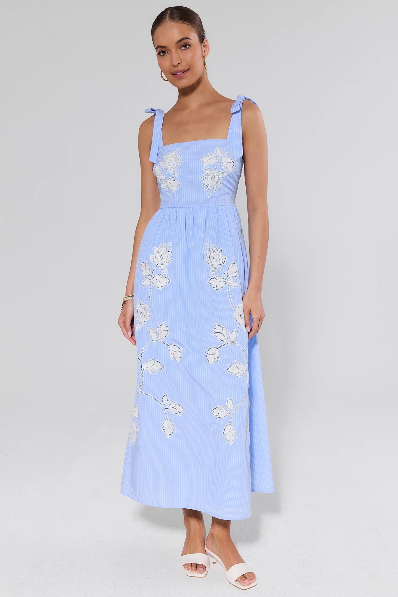 Woman wearing a light blue dress with floral embroidery on a white background