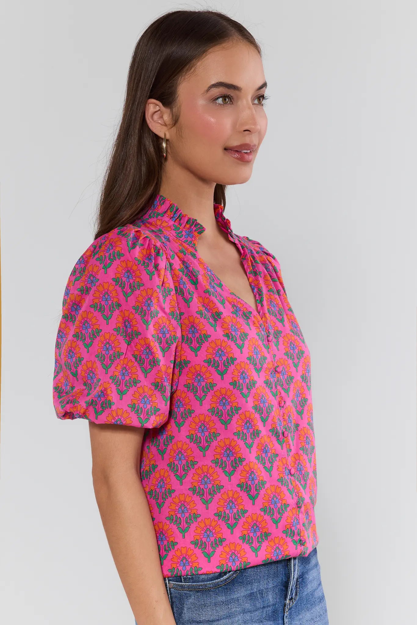 Woman wearing a patterned pink blouse against a plain background