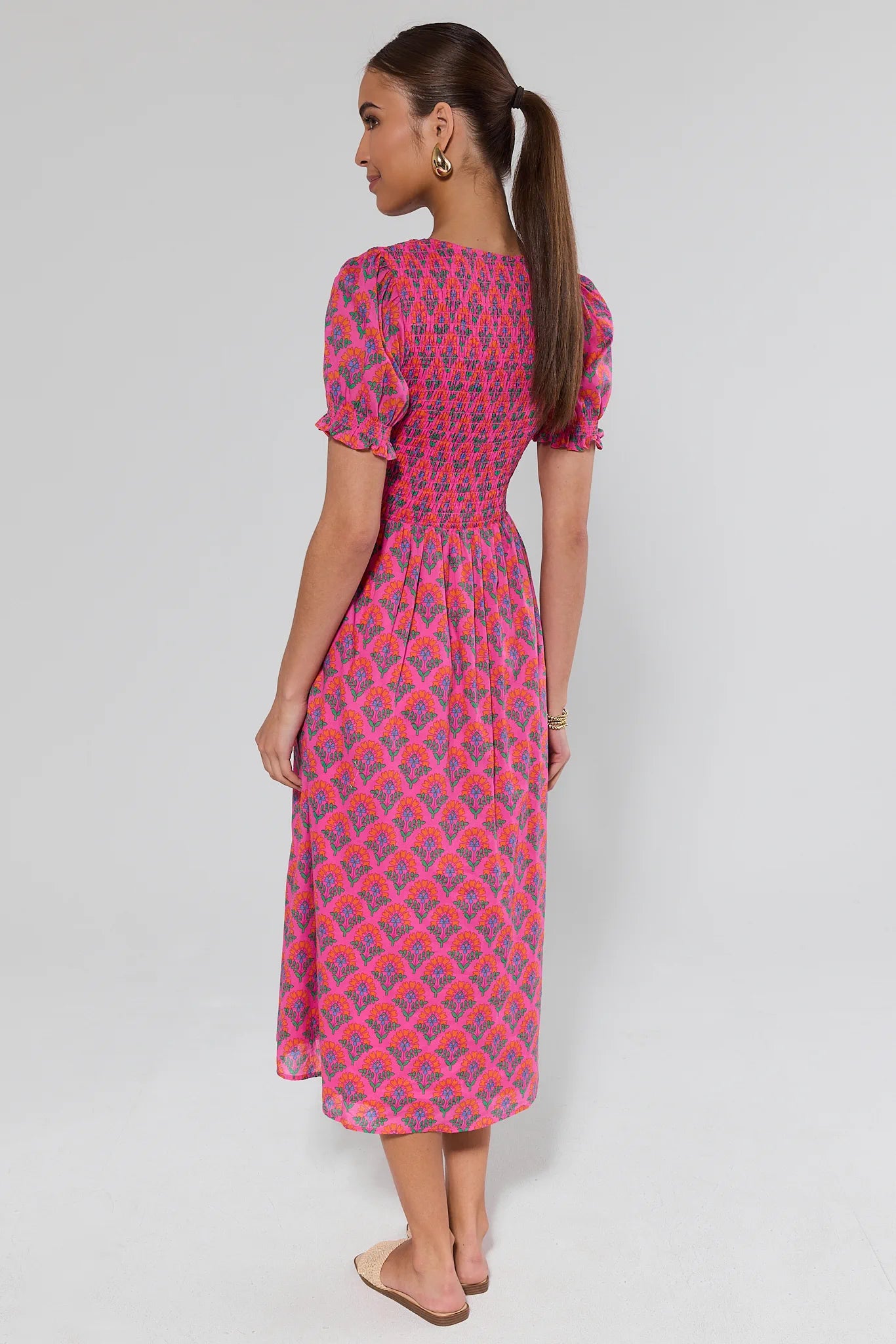 Woman wearing a pink patterned dress on a white background