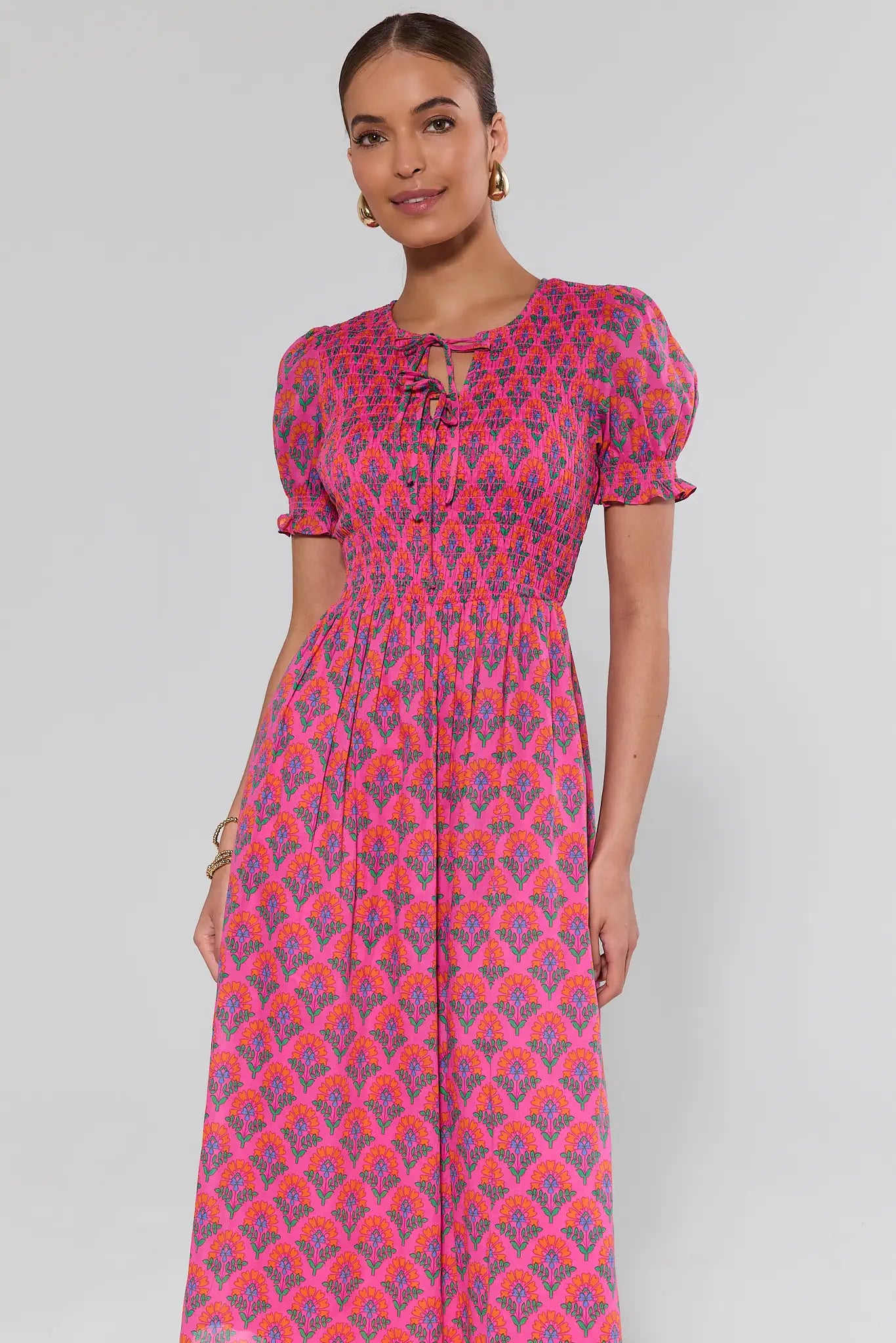 Woman wearing a pink and purple patterned dress on a plain background