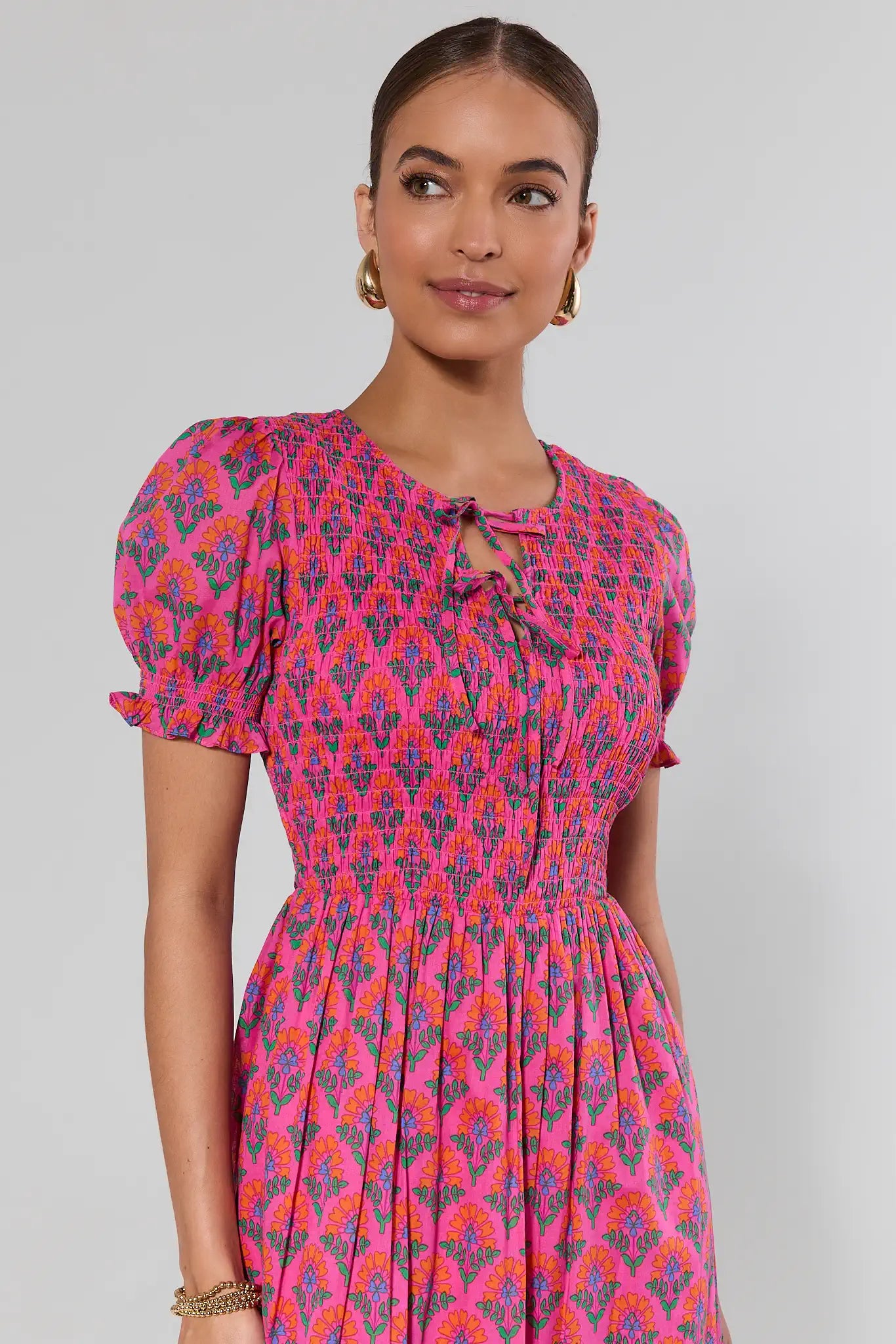 Woman wearing a pink and purple patterned dress against a gray background