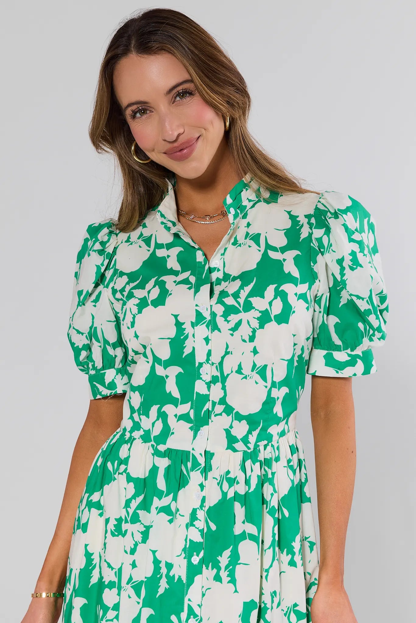 close up Woman wearing a green and white floral dress against a plain background