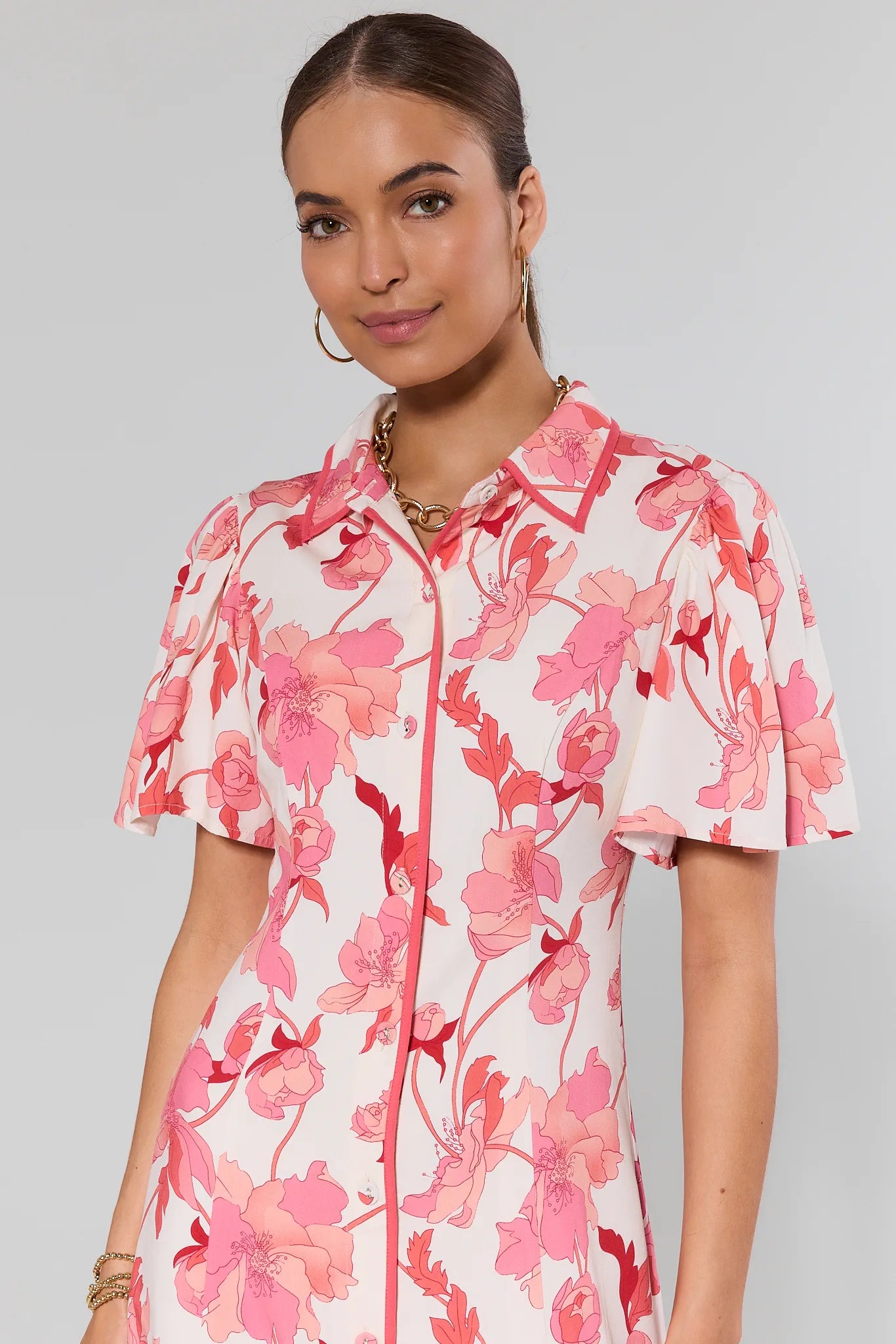 Woman wearing a pink floral dress against a gray background