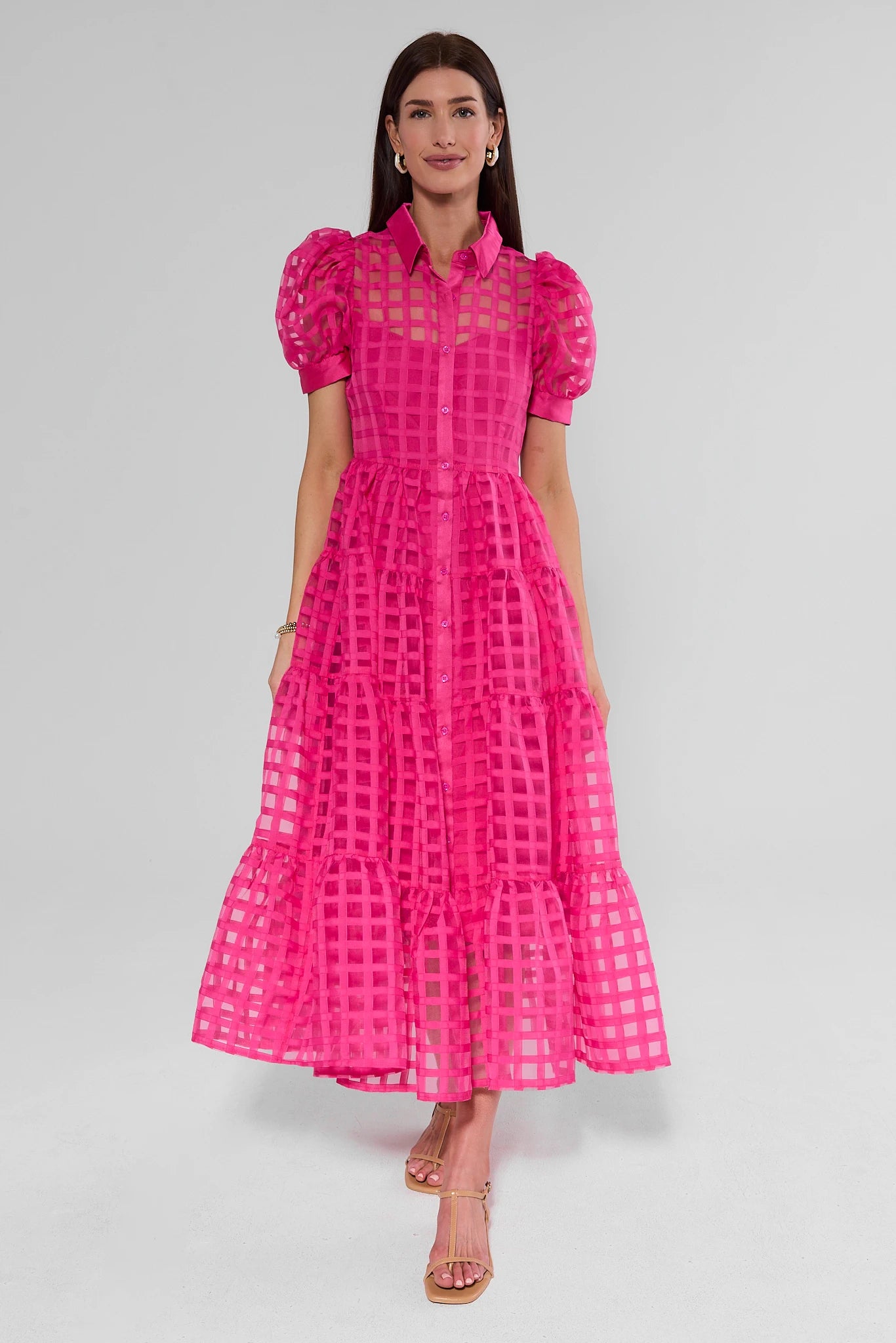 Woman wearing a bright pink dress with a grid pattern on a gray background