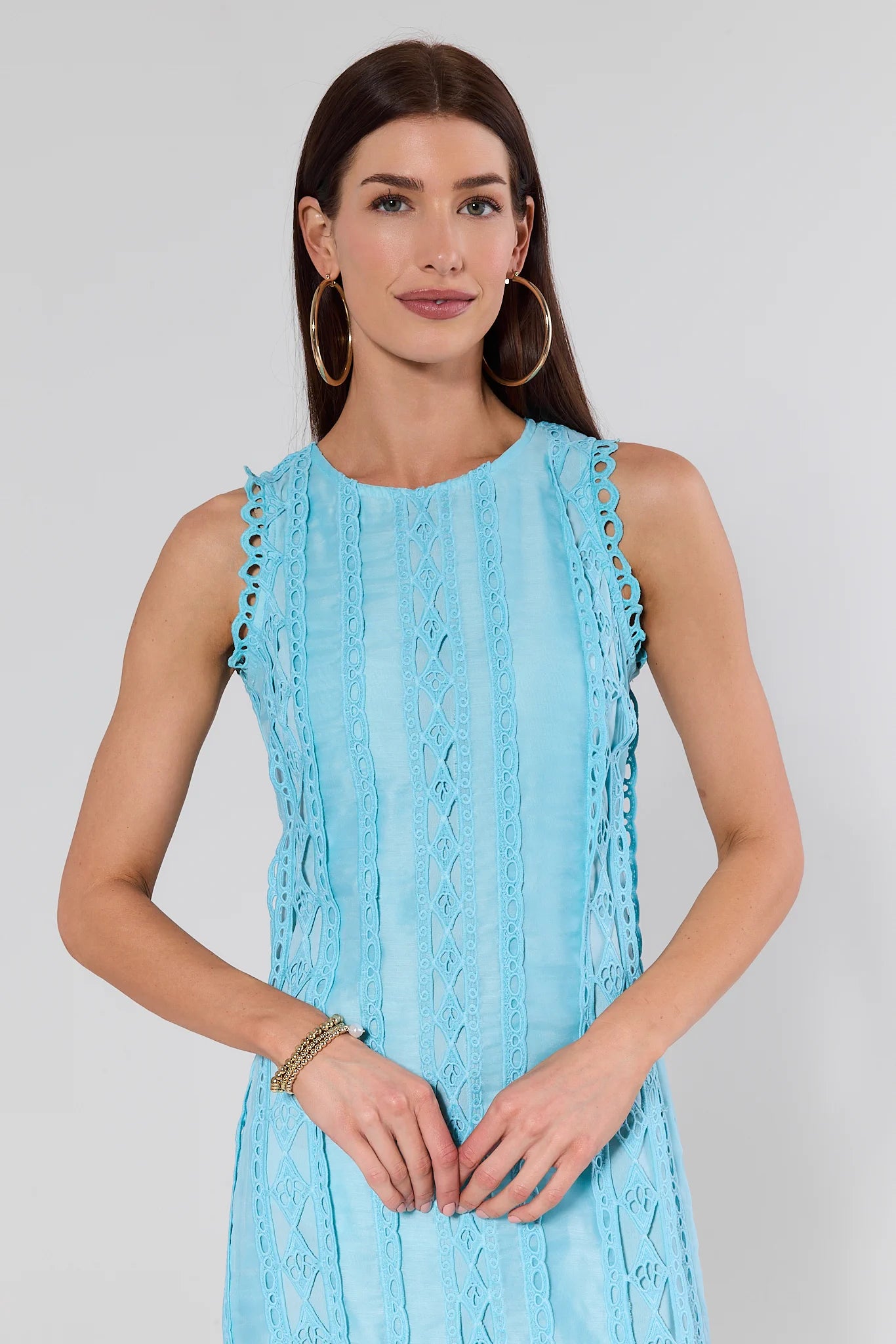 Woman wearing a light blue dress with ruffled details on a plain background