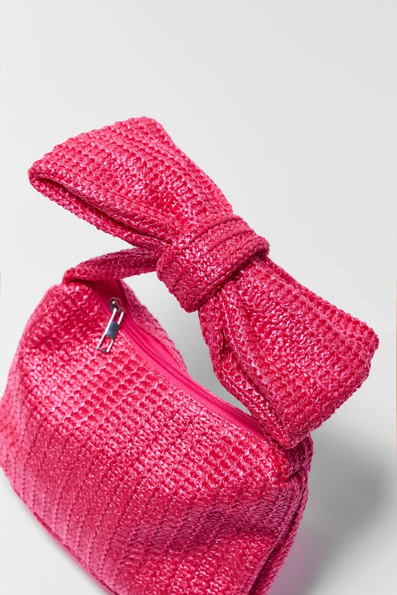 Pink textured pouch with a bow on a light gray background