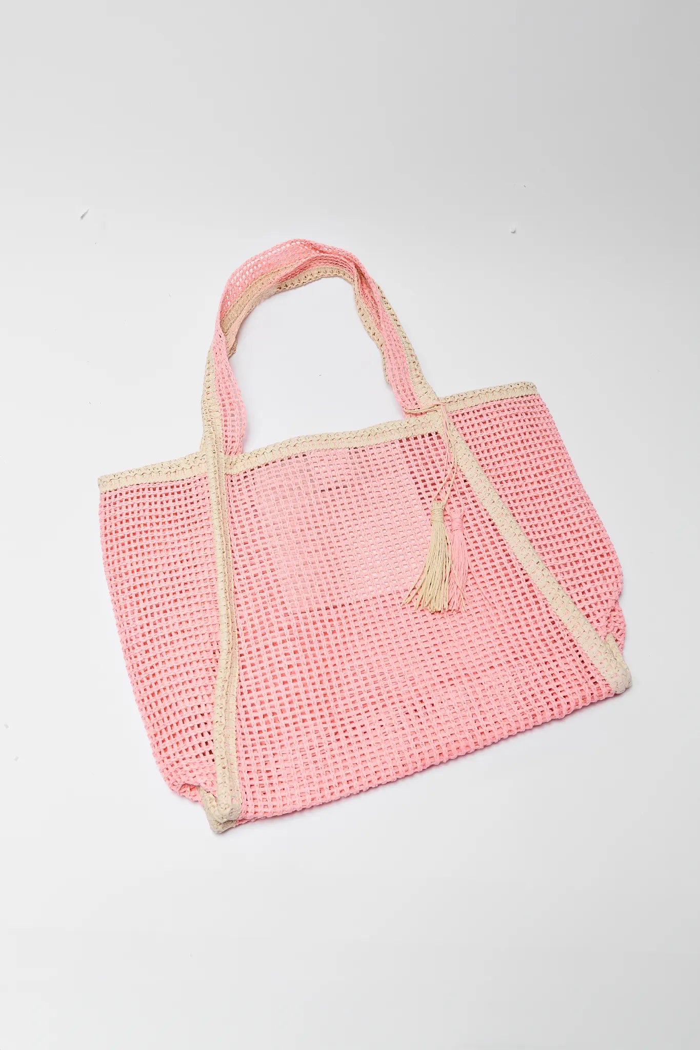 Pink woven tote bag with beige trim on a light gray background