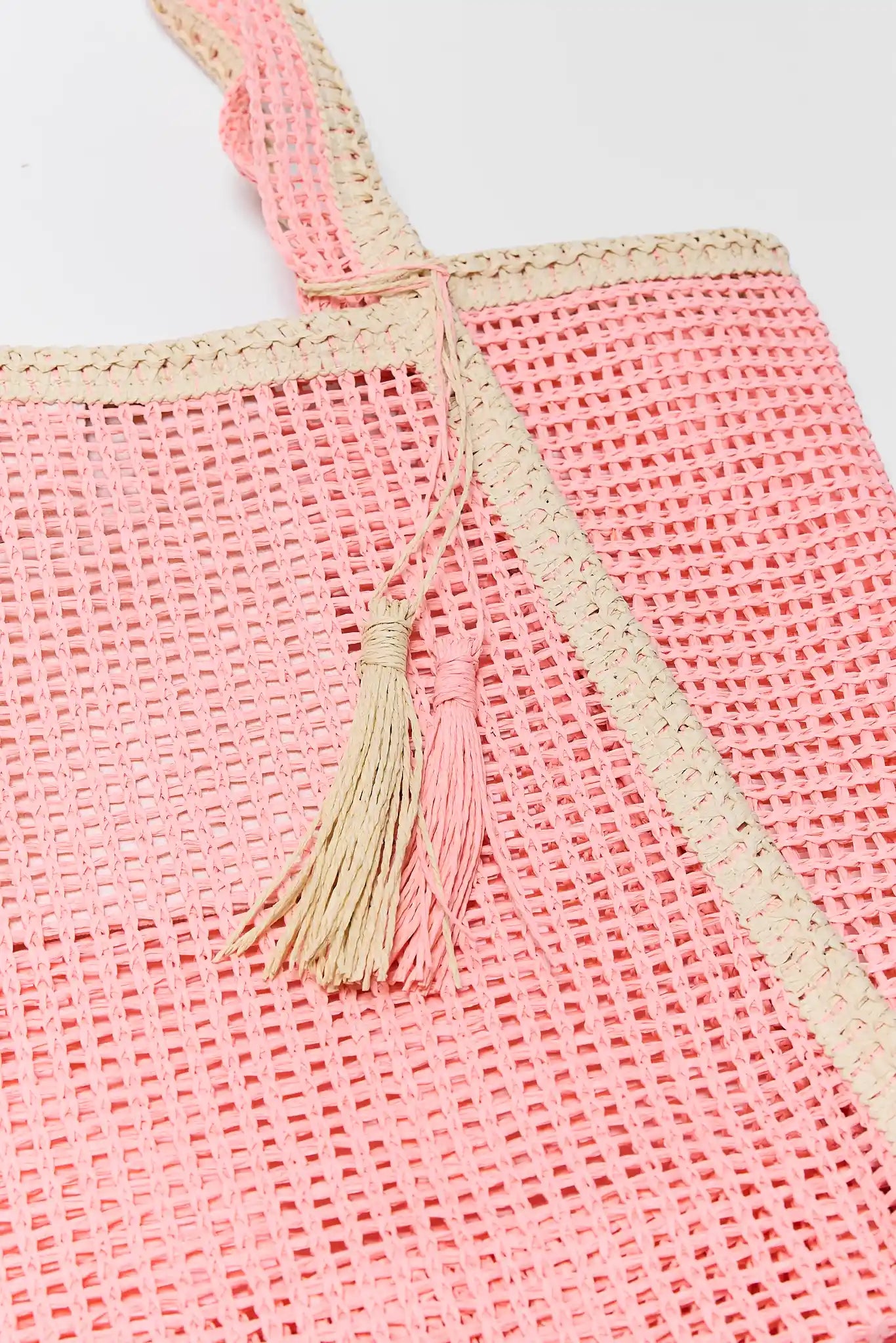 close up Pink woven bag with a tassel on a light gray background