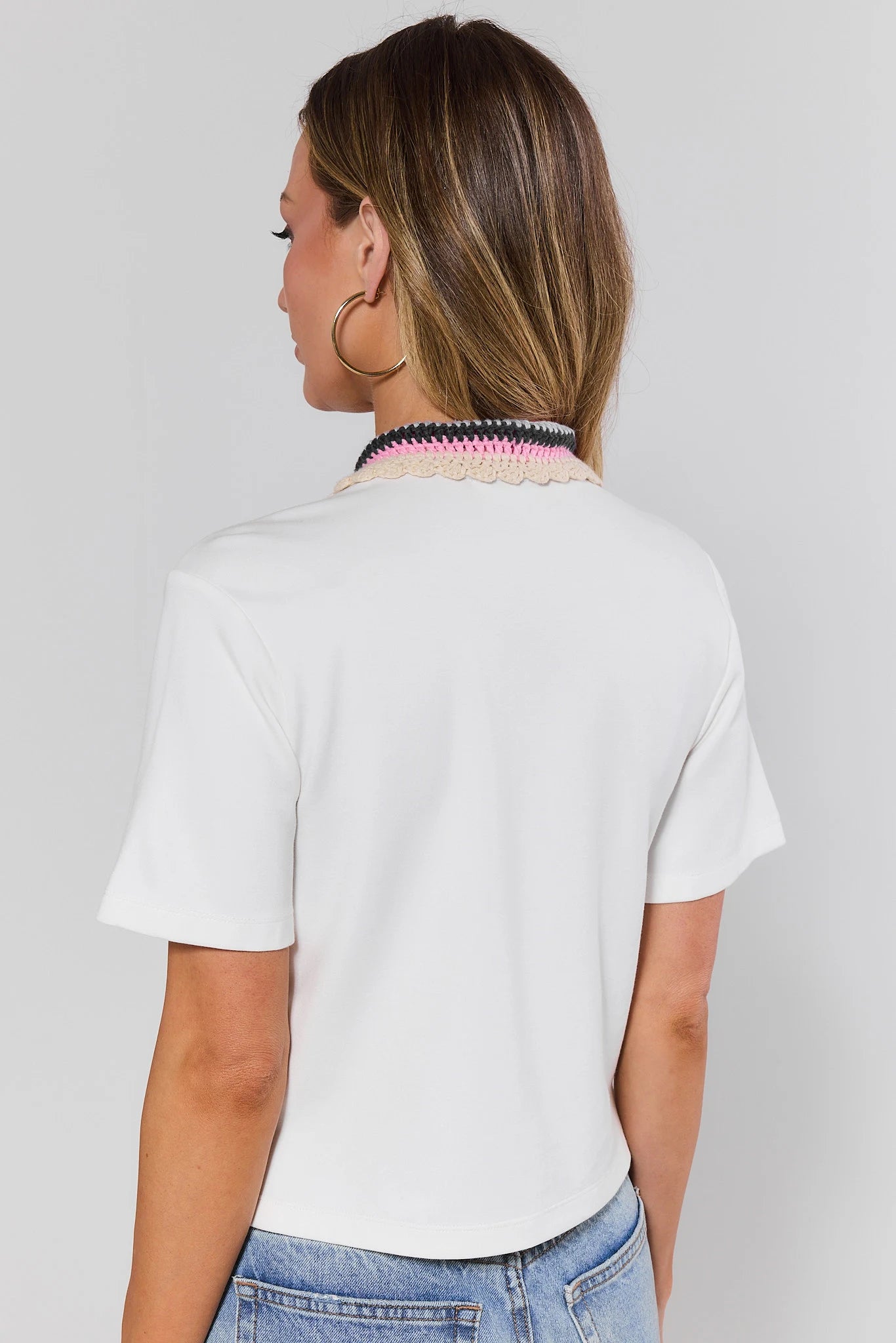 Person standing wearing a white t-shirt and blue jeans on a plain background