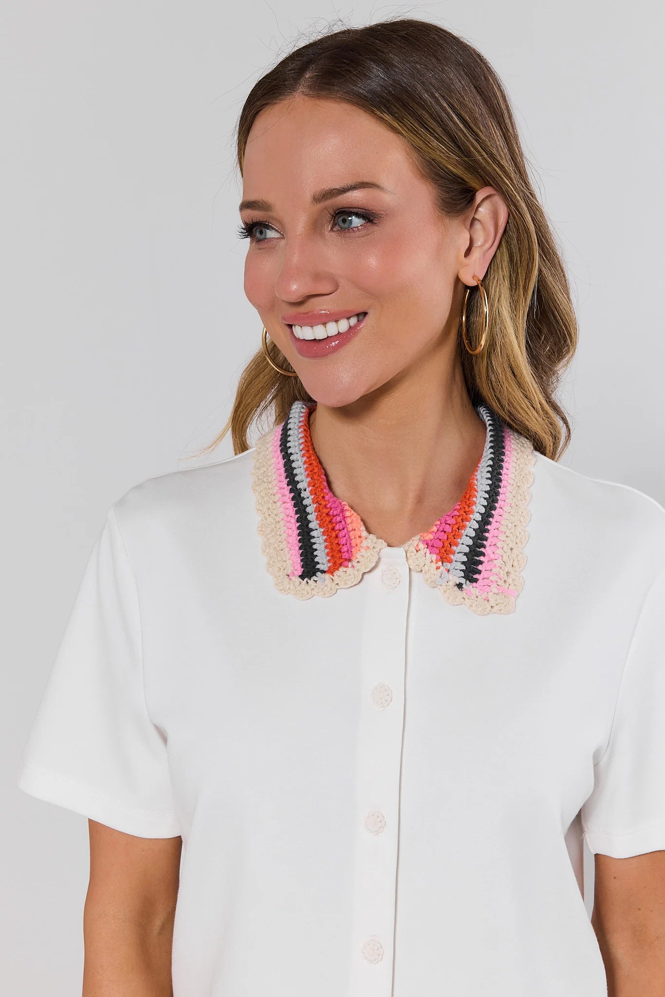 close up Woman wearing a white shirt with a colorful collar against a plain background