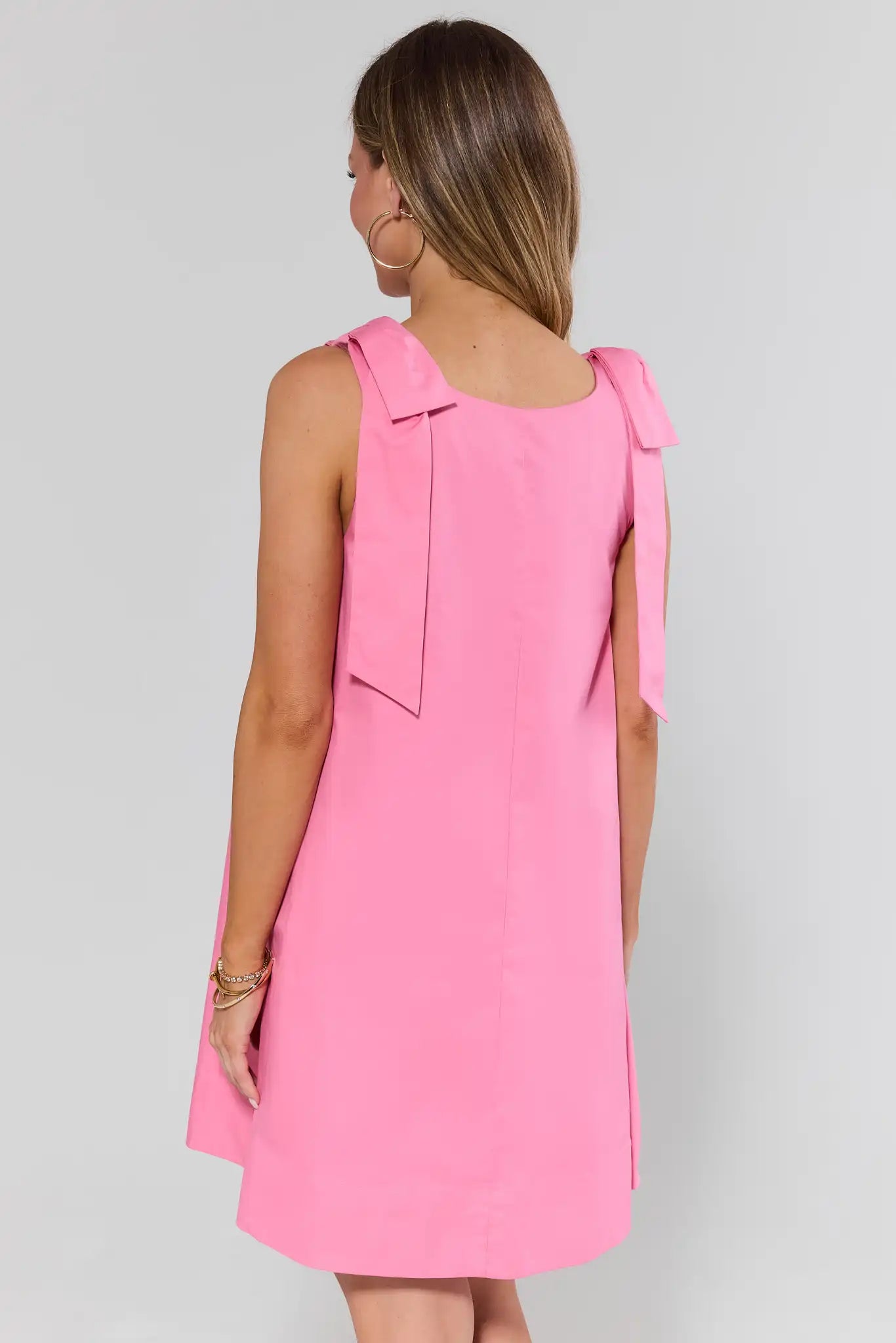 standing Pink dress with bow details on a gray background