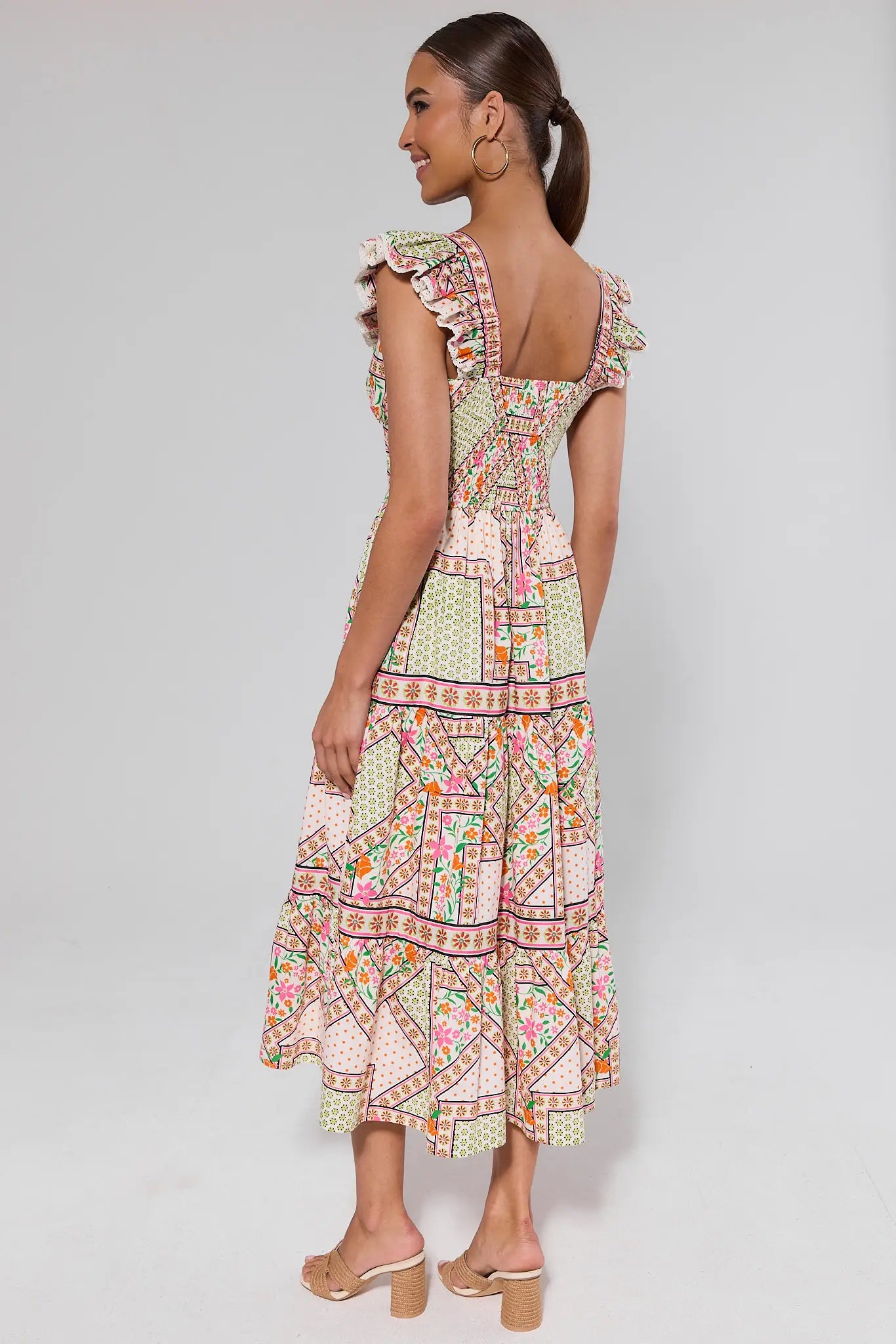 side shot Woman wearing a patterned dress on a plain background