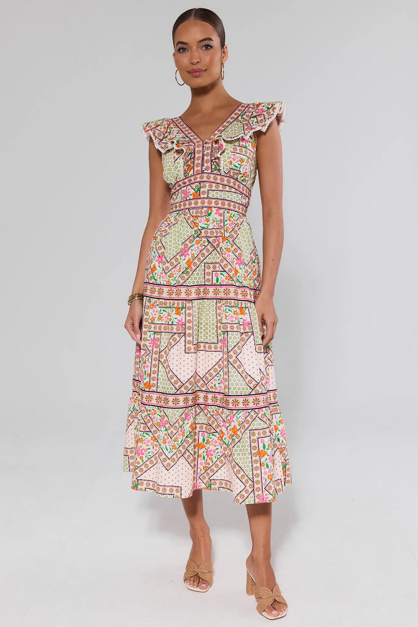 Woman wearing a colorful patterned dress and heels on a plain background