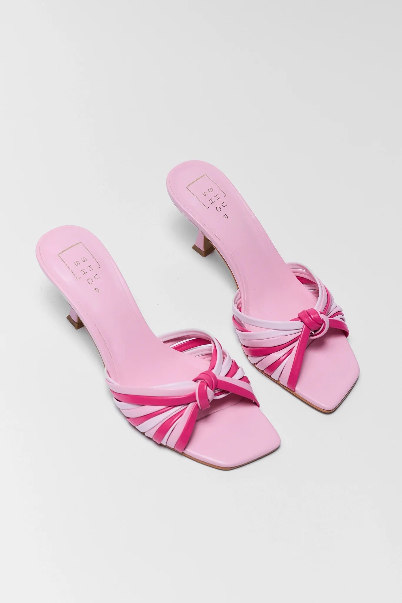 Pair of pink sandals with bow details on a gray background
