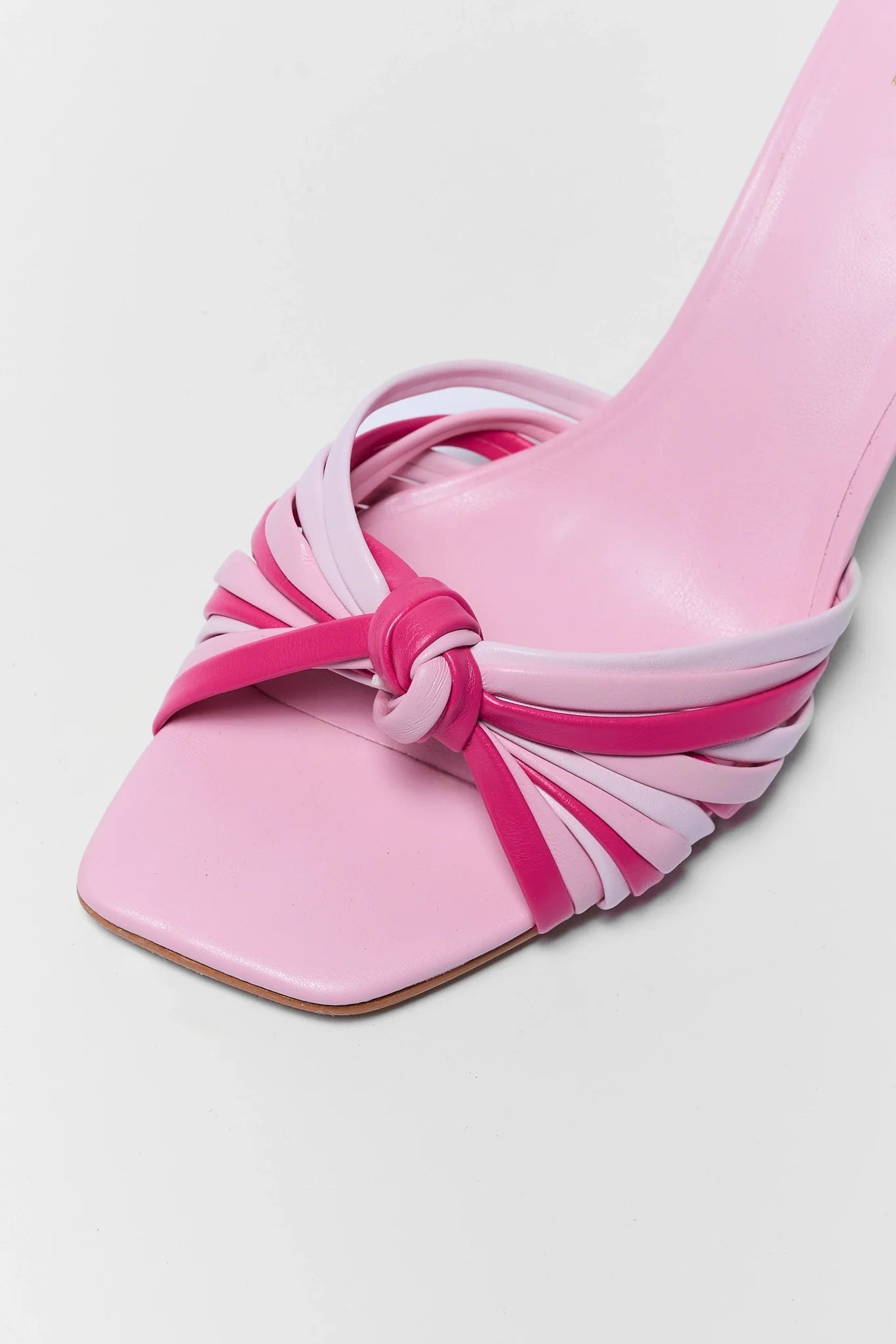 Pink sandal with a knot detail on a light gray background close up