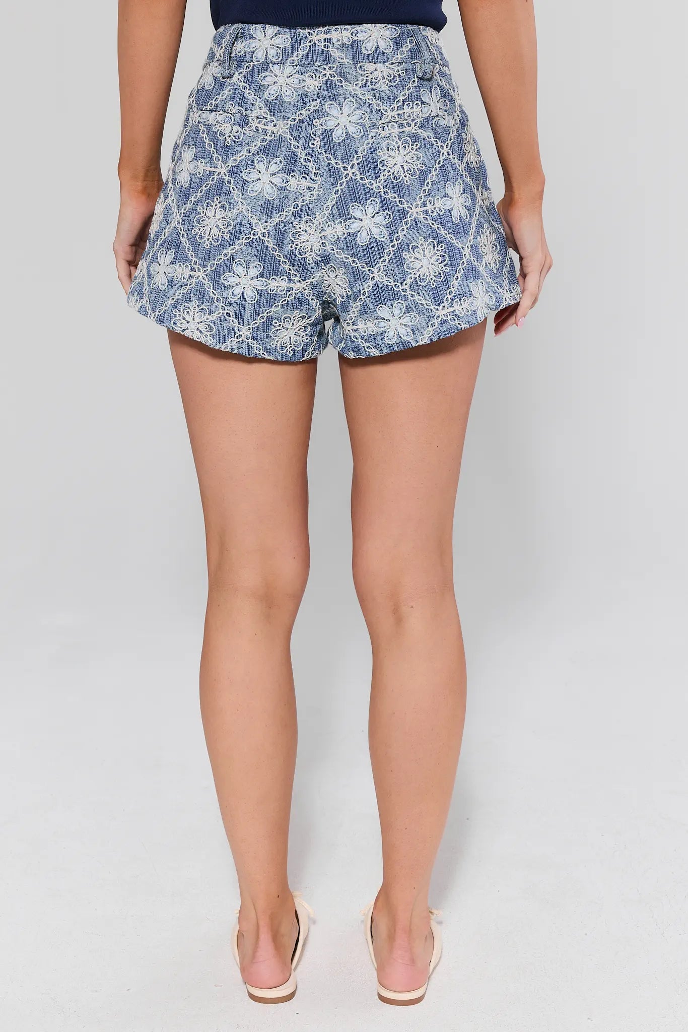 Person wearing blue floral shorts on a white background