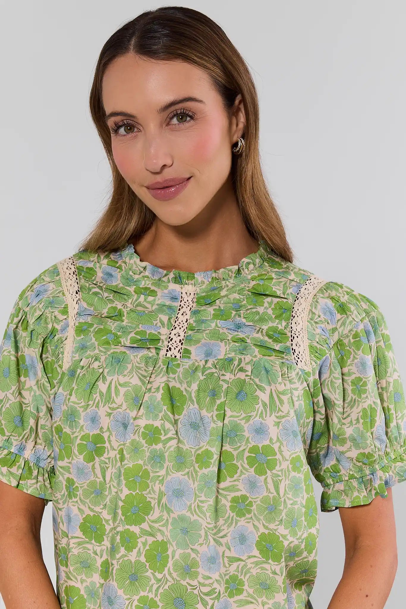 close up Woman wearing a green floral dress with lace details on a plain background