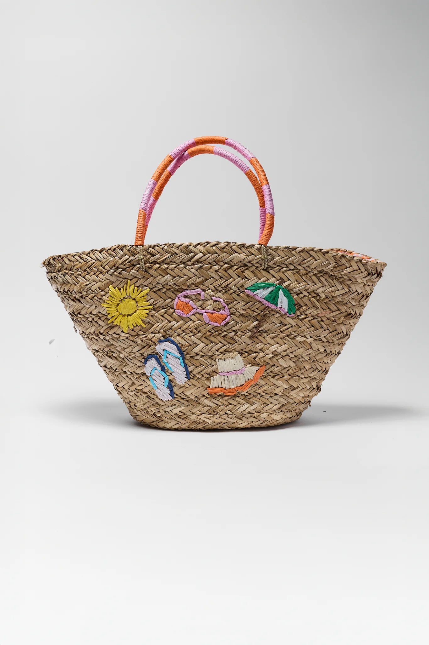 Woven straw bag with colorful beach-themed decorations on a white background