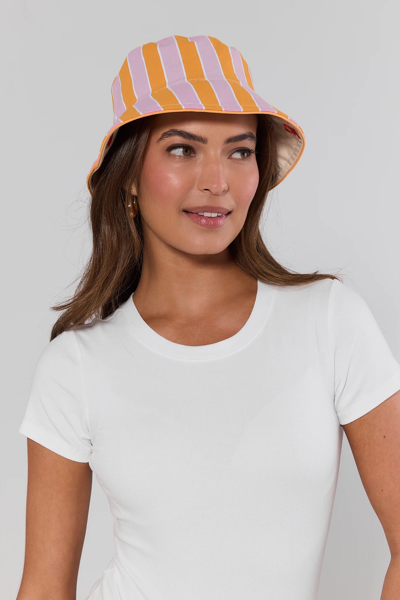 Woman wearing a colorful striped bucket hat on a plain background