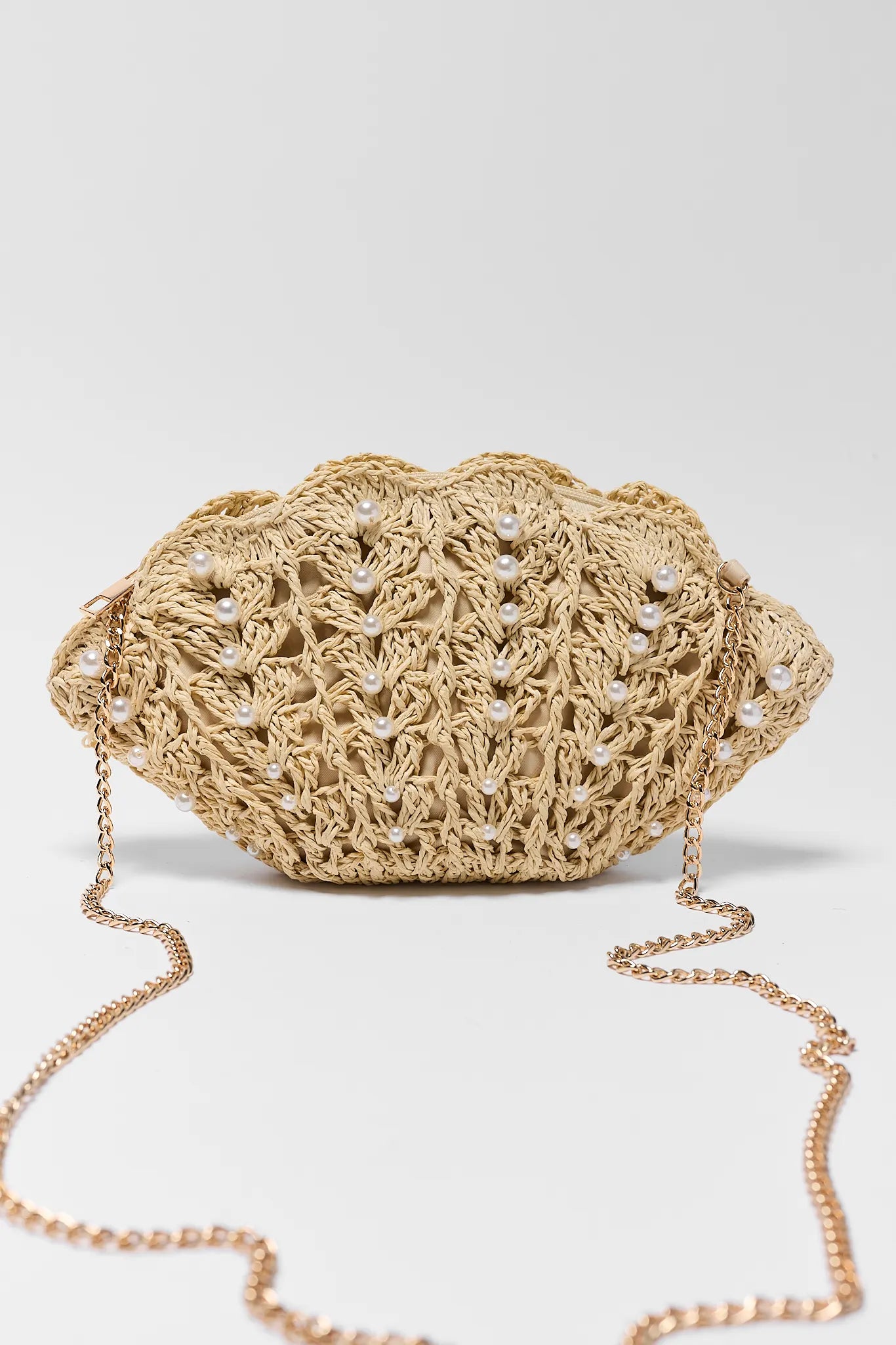 Crocheted handbag with pearl embellishments on a light gray background