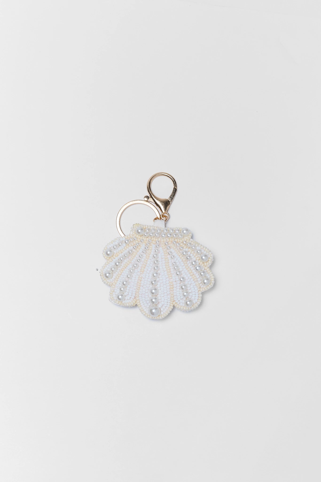 Shell-shaped keychain with a gold ring on a white background