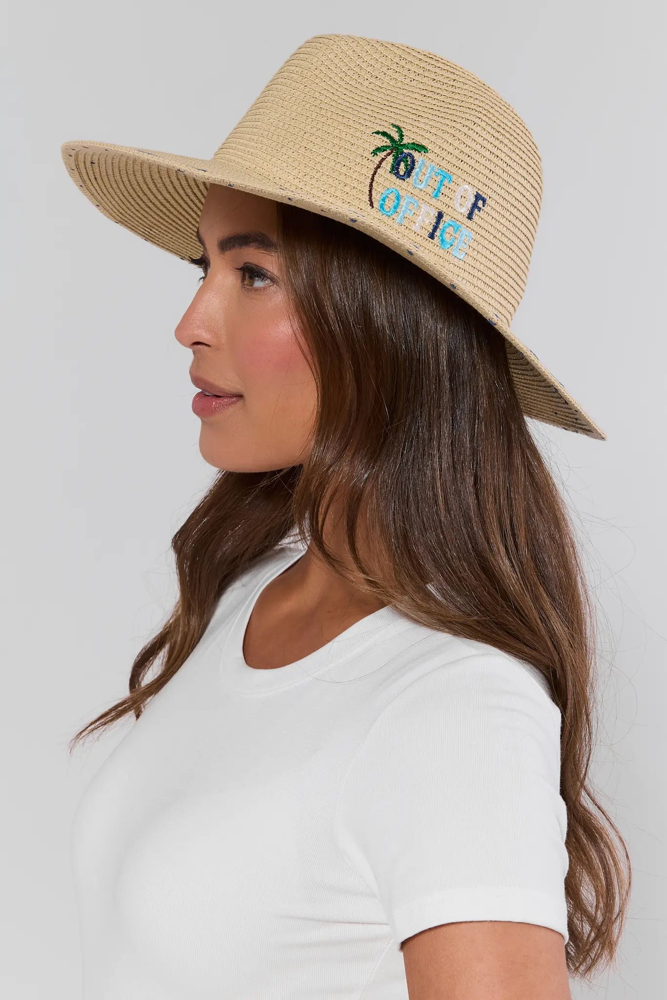 Woman wearing a straw hat with text and palm tree design on a plain background