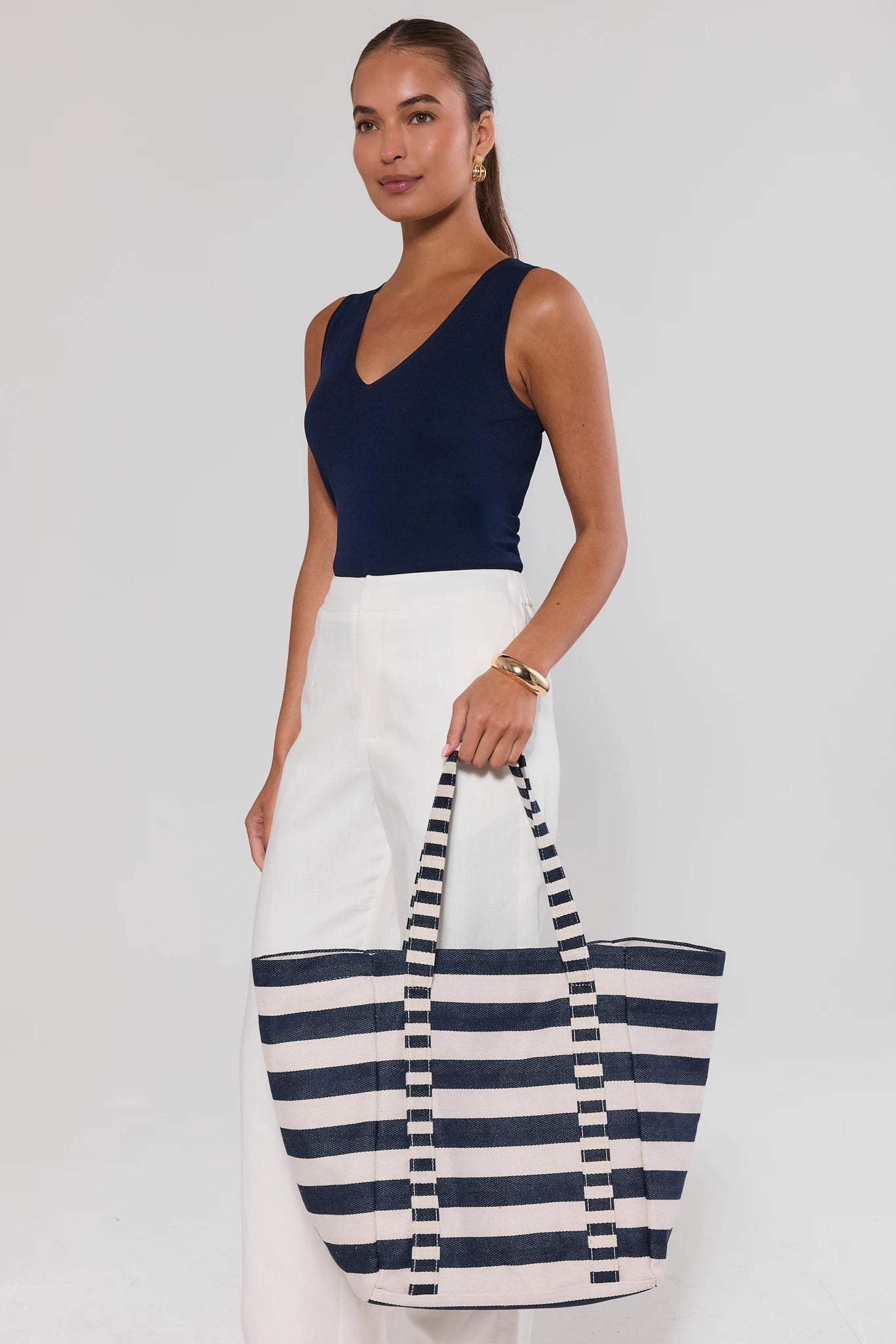 woman holding Navy and white striped tote bag on a light gray background