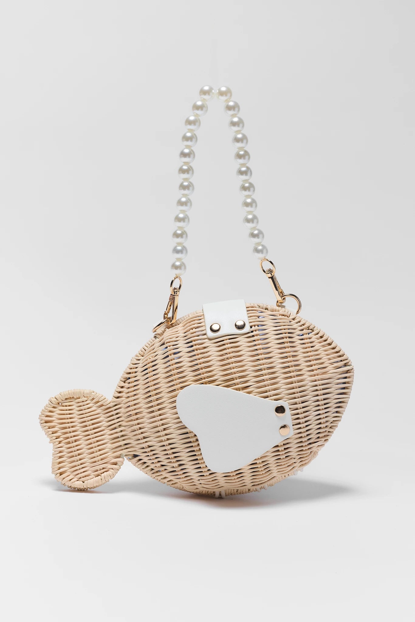 Wicker handbag shaped like a fish with pearl handle on a light gray background