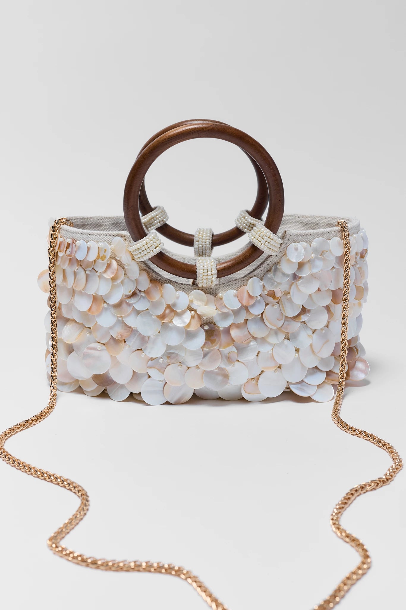 Elegant handbag with floral design and wooden handle on a white background