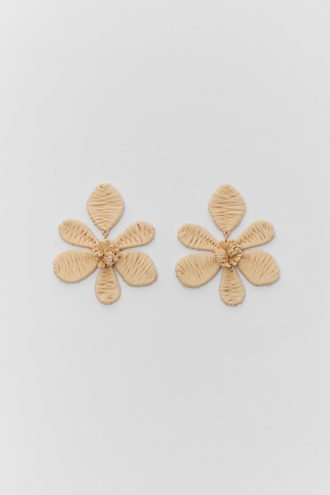 Pair of beige flower-shaped earrings on a light gray background