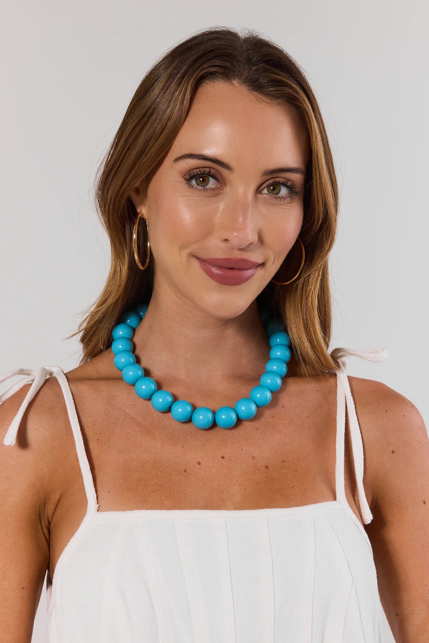 Woman wearing a turquoise necklace against a plain background