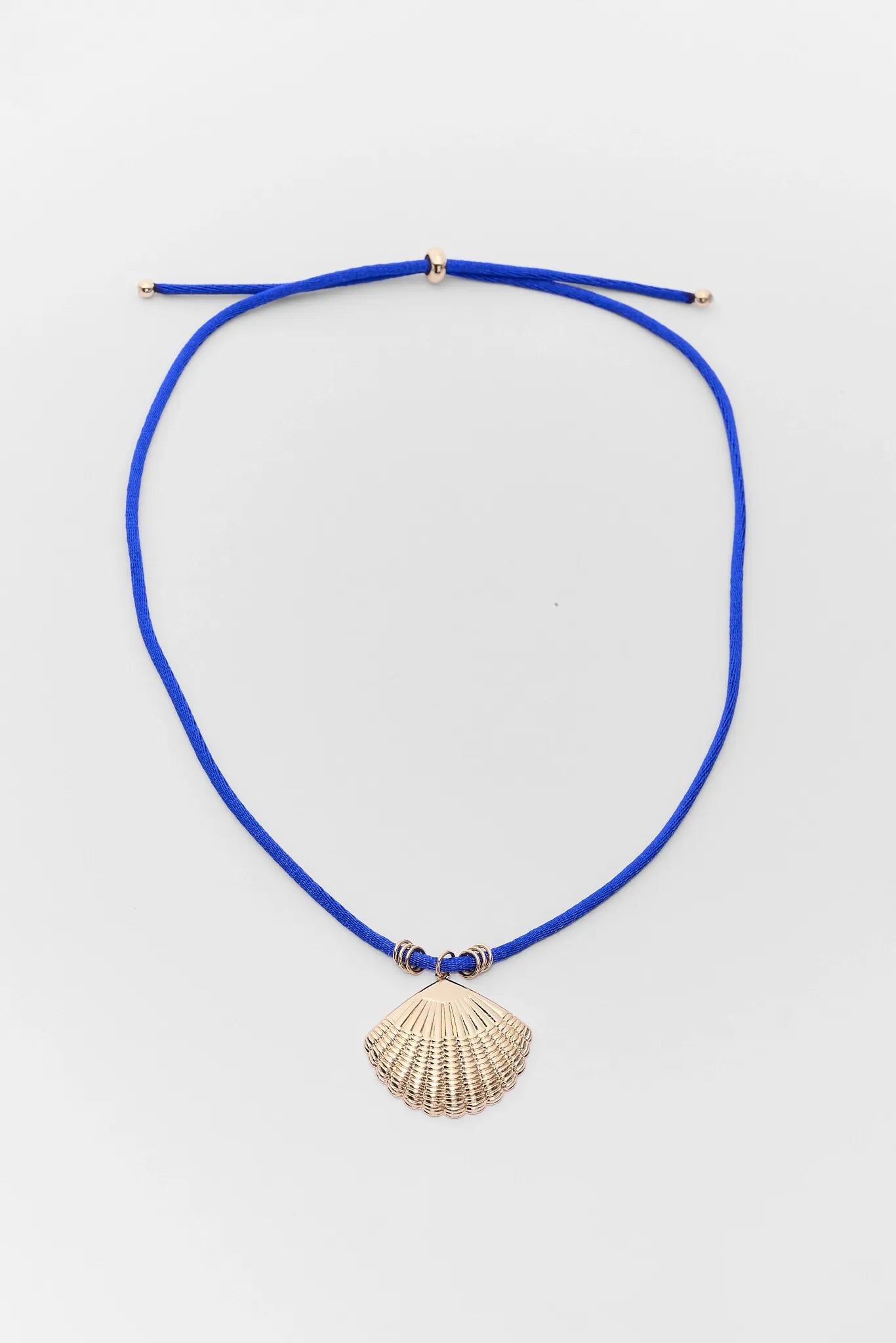Blue necklace with a shell pendant on a light gray background