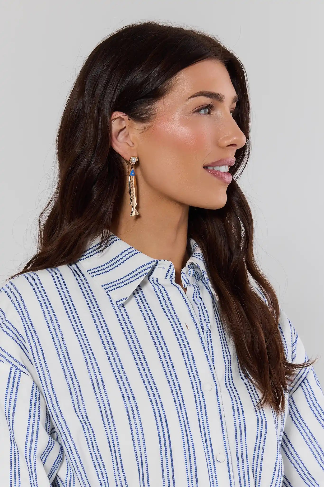 Woman wearing a blue and white striped shirt against a plain background